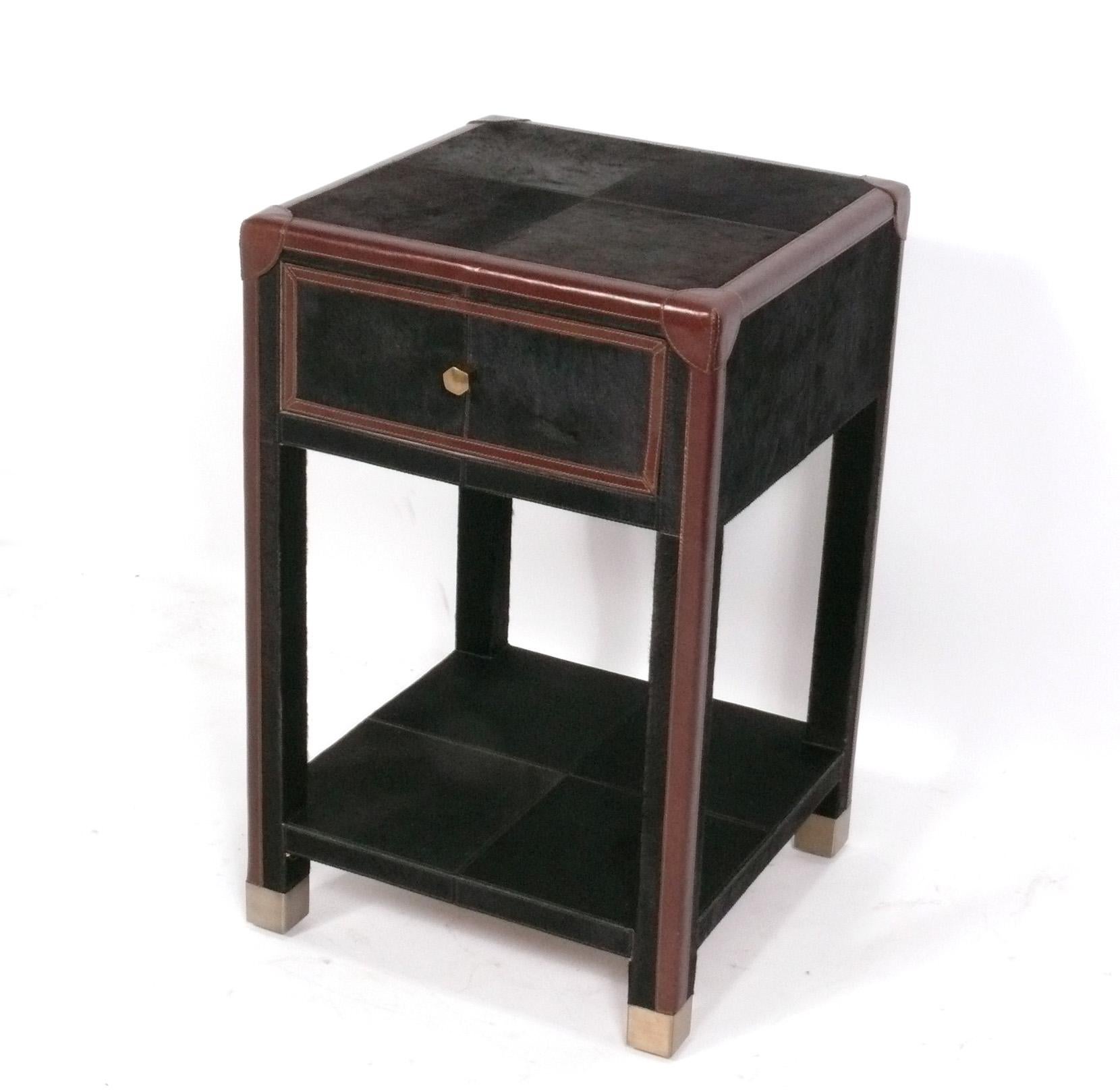 Elegant cowhide and leather nightstand, by Made Goods, American, circa 2020s. Original retail price $2400. This piece is a versatile size and can be used as a nightstand, end, or side table. It is constructed of hair on hide cowhide, leather, and