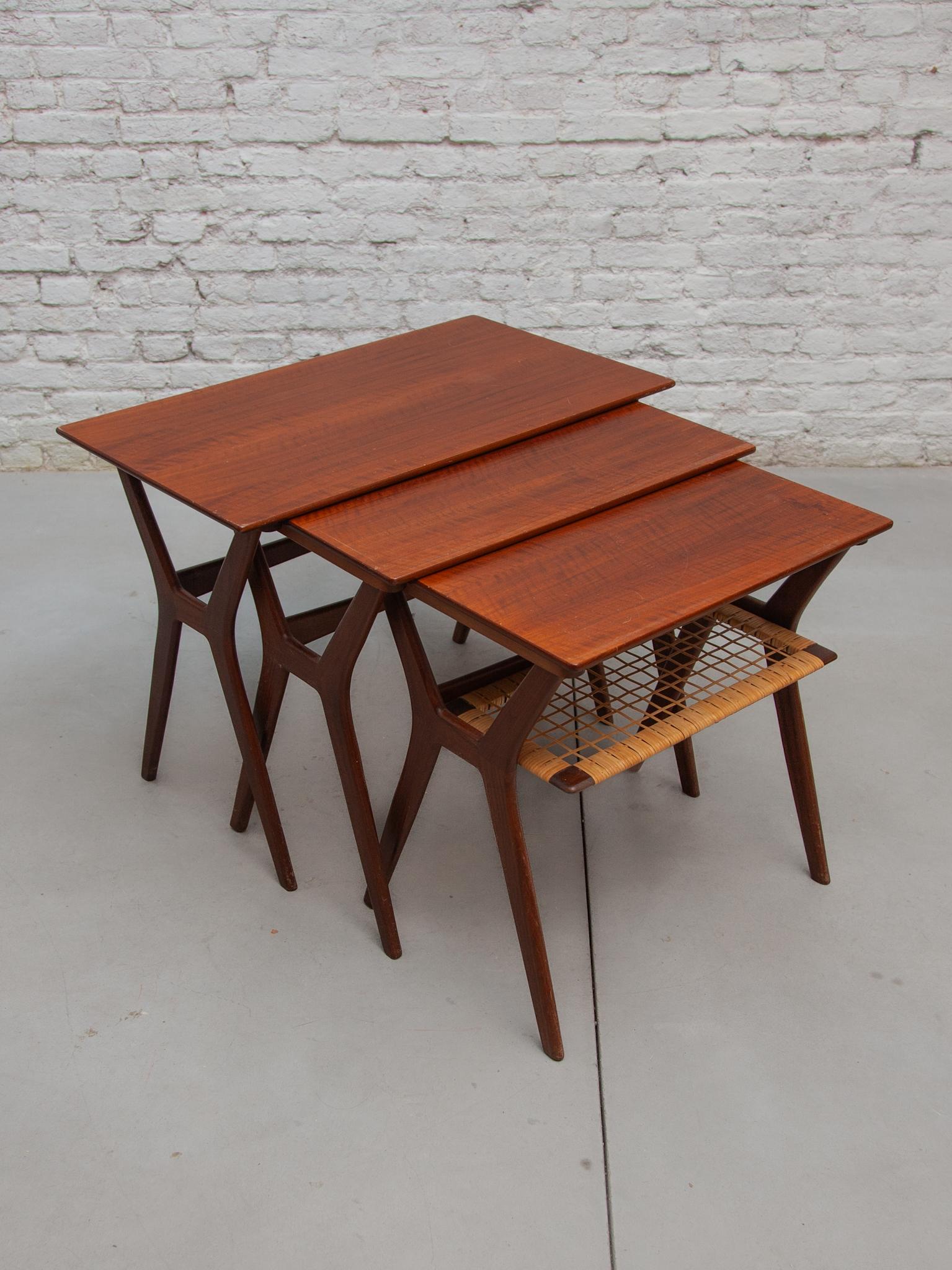 Mid-century teak nesting tables perfectly slide into each other forming a beautiful nest of tables. The lowest table has a cane webbing lower tier. In perfect good condition.Designed by Johannes Andersen for Silkeborg, 1960s Denmark. Dimensions: