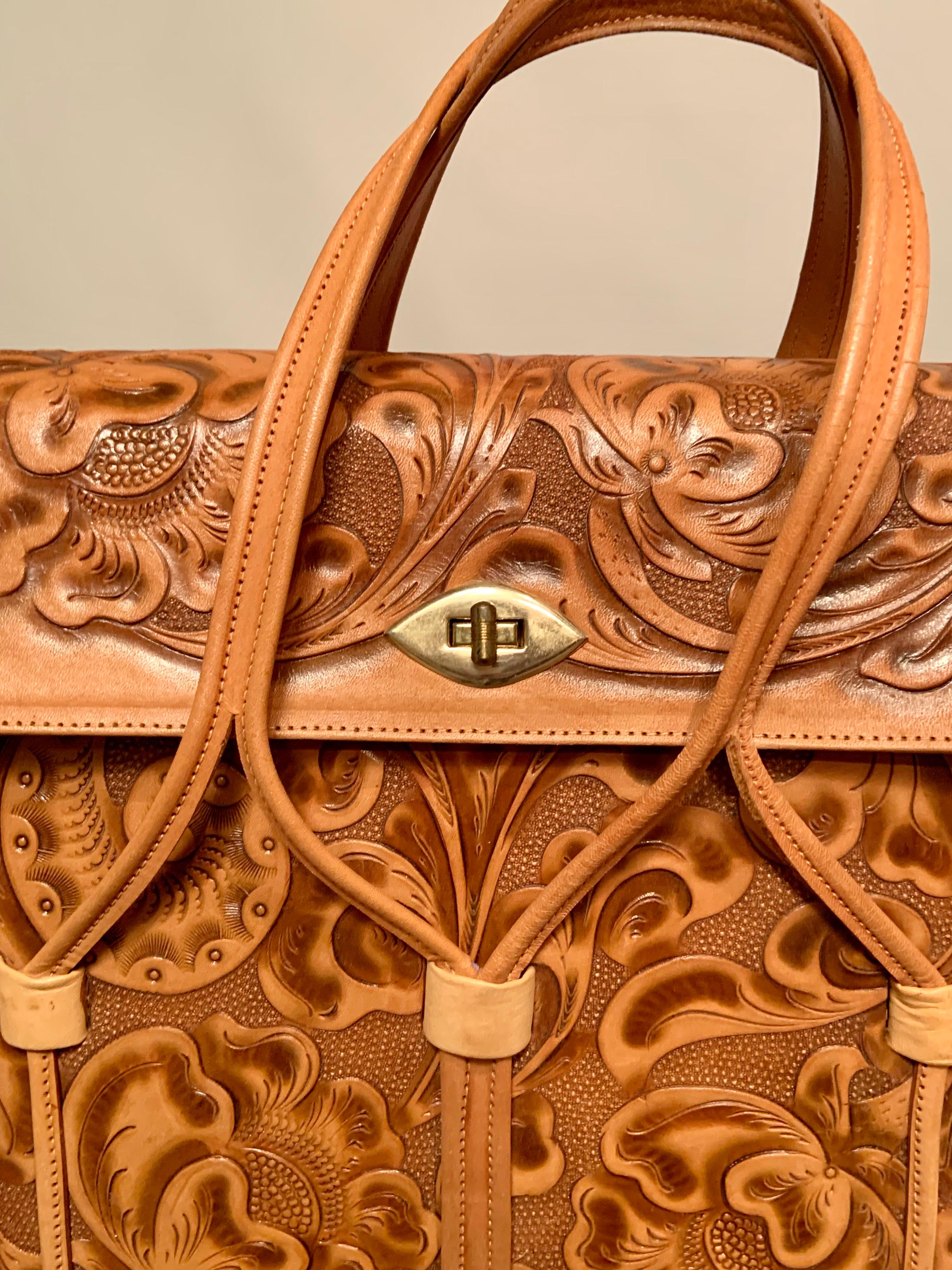 Made in Mexico , this is the largest hand tooled leather bag  that I have ever seen. A floral design is tooled into the leather and three straps are used to make the two handles.  The bag is decorated on the front, sides, back and even the bottom,