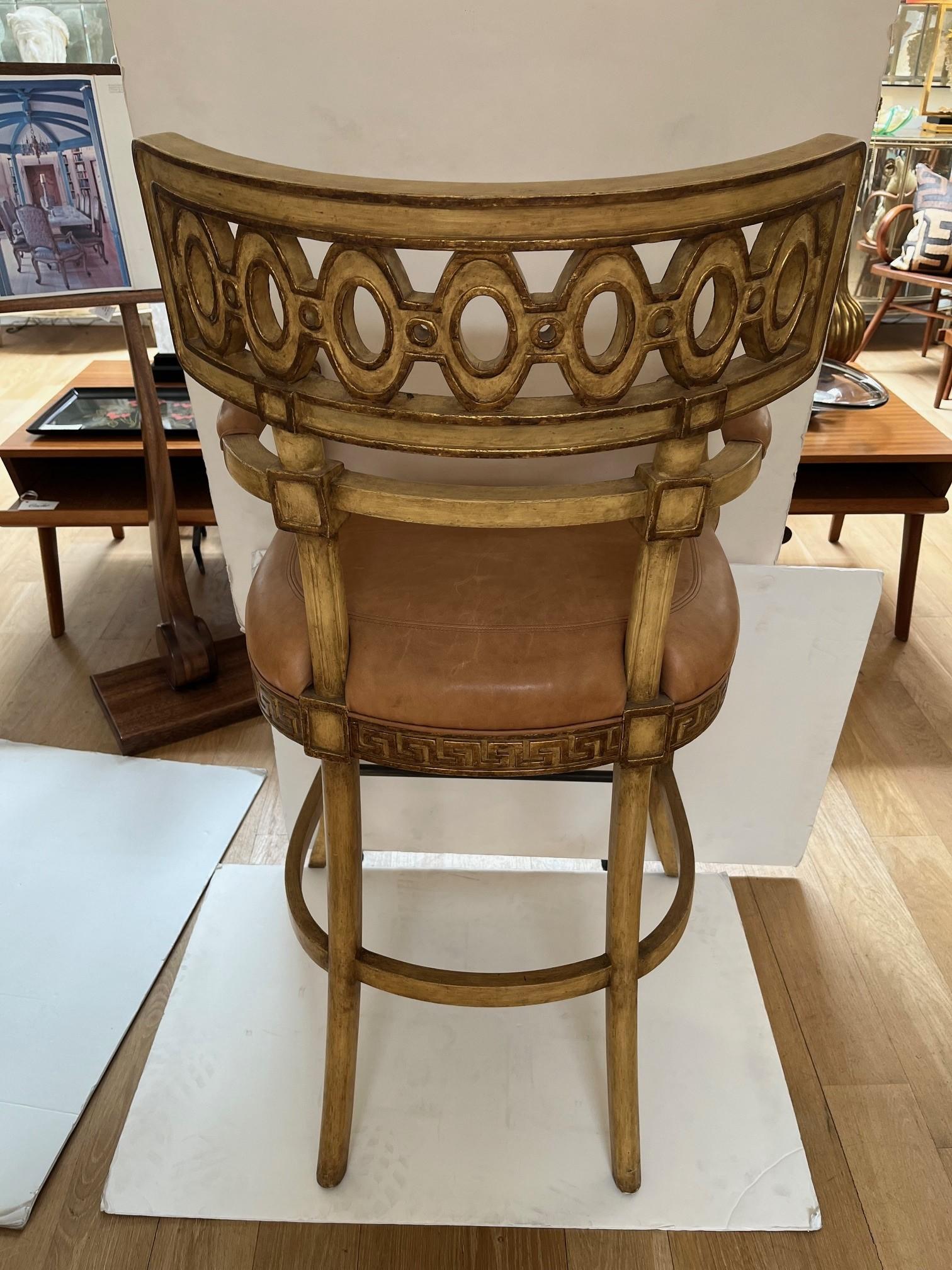 Made to Order Carved Venetian Bar Stool, Antique Painted Finish with Gilded Detail, Open Back with Carved Detail of the Back, Upholstered in Stitched Caramel Leather Seat and Padded Upholstered Armrest, Greek Key Detail around the Seat, this is the