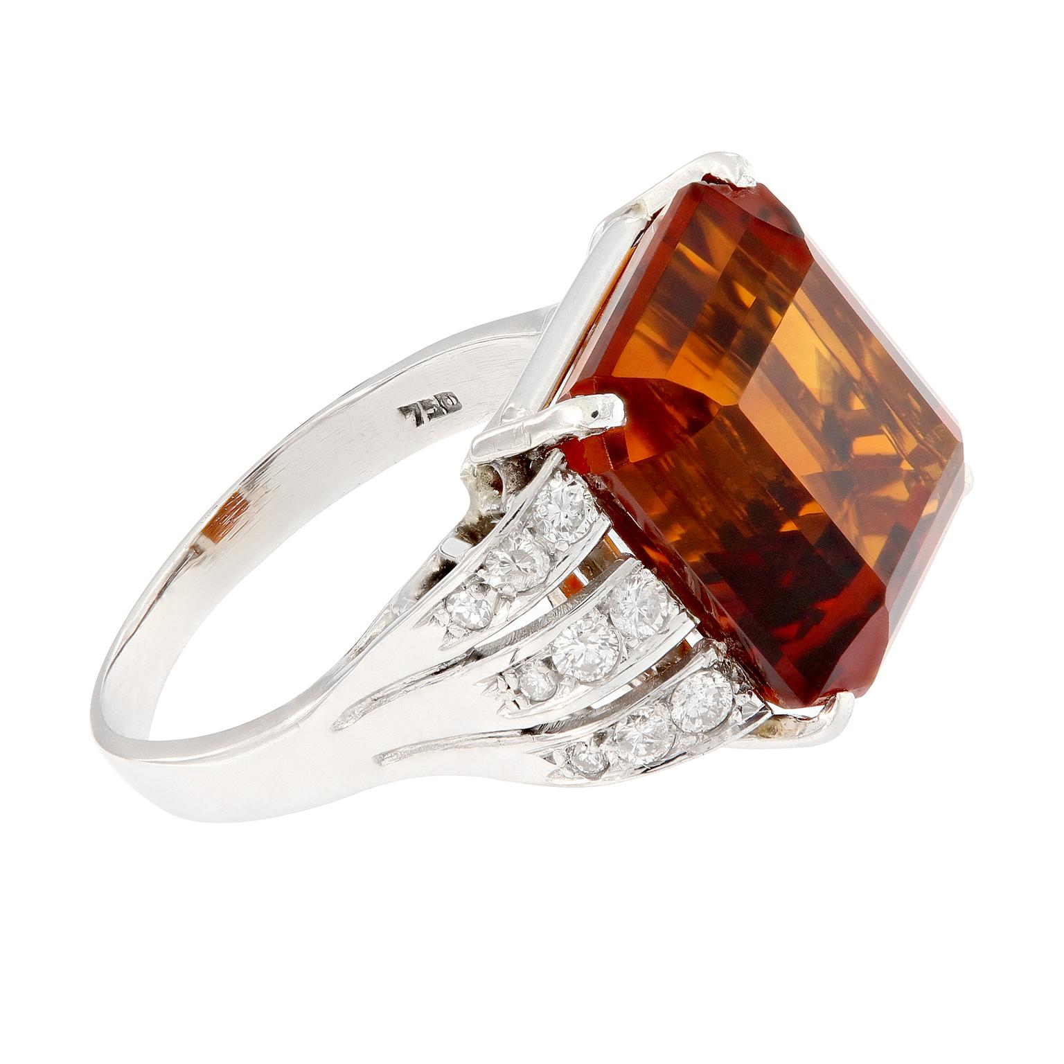 The burnt orange color of this Madeira citrine is a brilliant and bold fashion statement! Ring centers around an over nine carat citrine accented with three rows of white diamonds running down the shank. This estate ring is constructed in 18k white