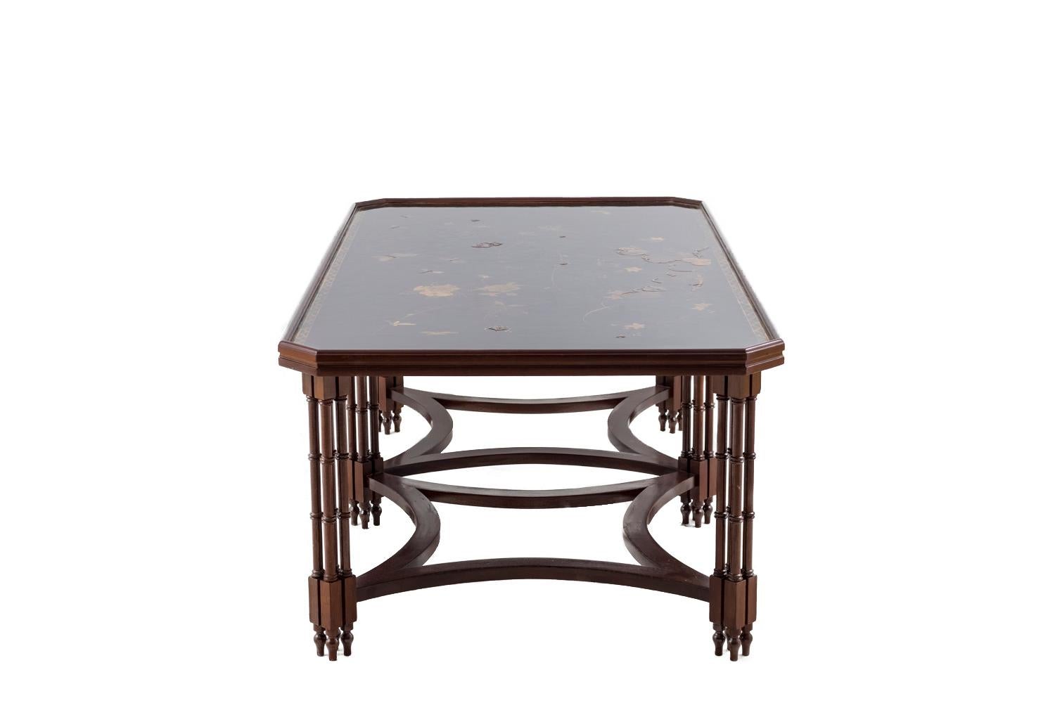 Veneered mahogany coffee table standing on six feet, each composed by four small bamboo imitation ringed columns. They’re linked together by two square stretchers with concaves edges. Moulded rectangular trays with canted corners, top in black