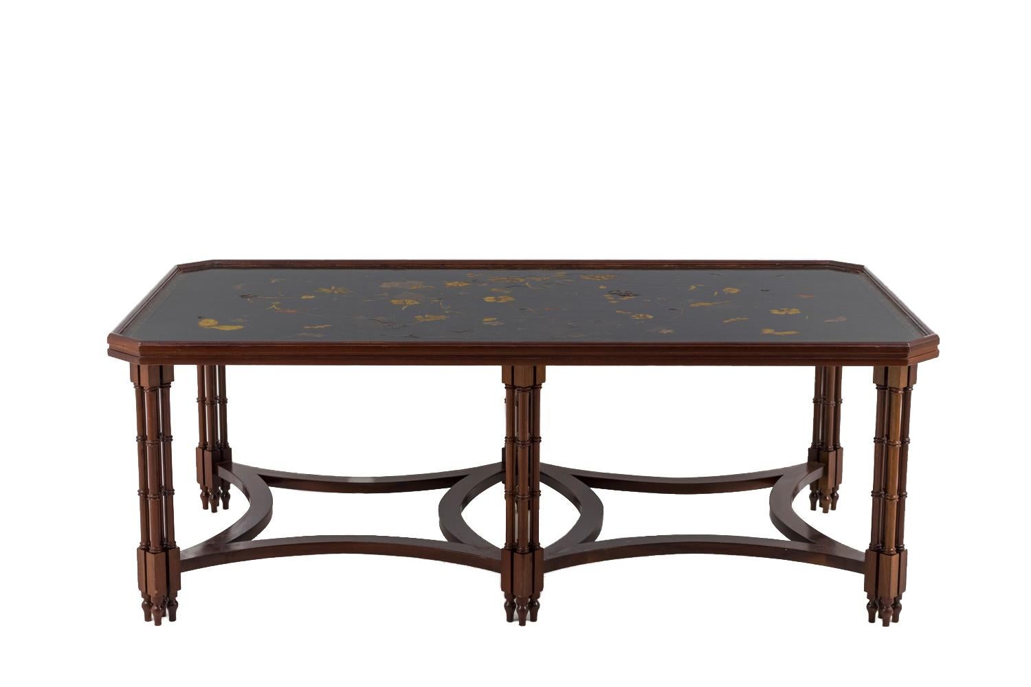 Veneered mahogany coffee table standing on six feet, each composed by four small bamboo imitation ringed columns. They’re linked together by two square stretchers with concaves edges. Moulded rectangular trays with canted corners, top in black