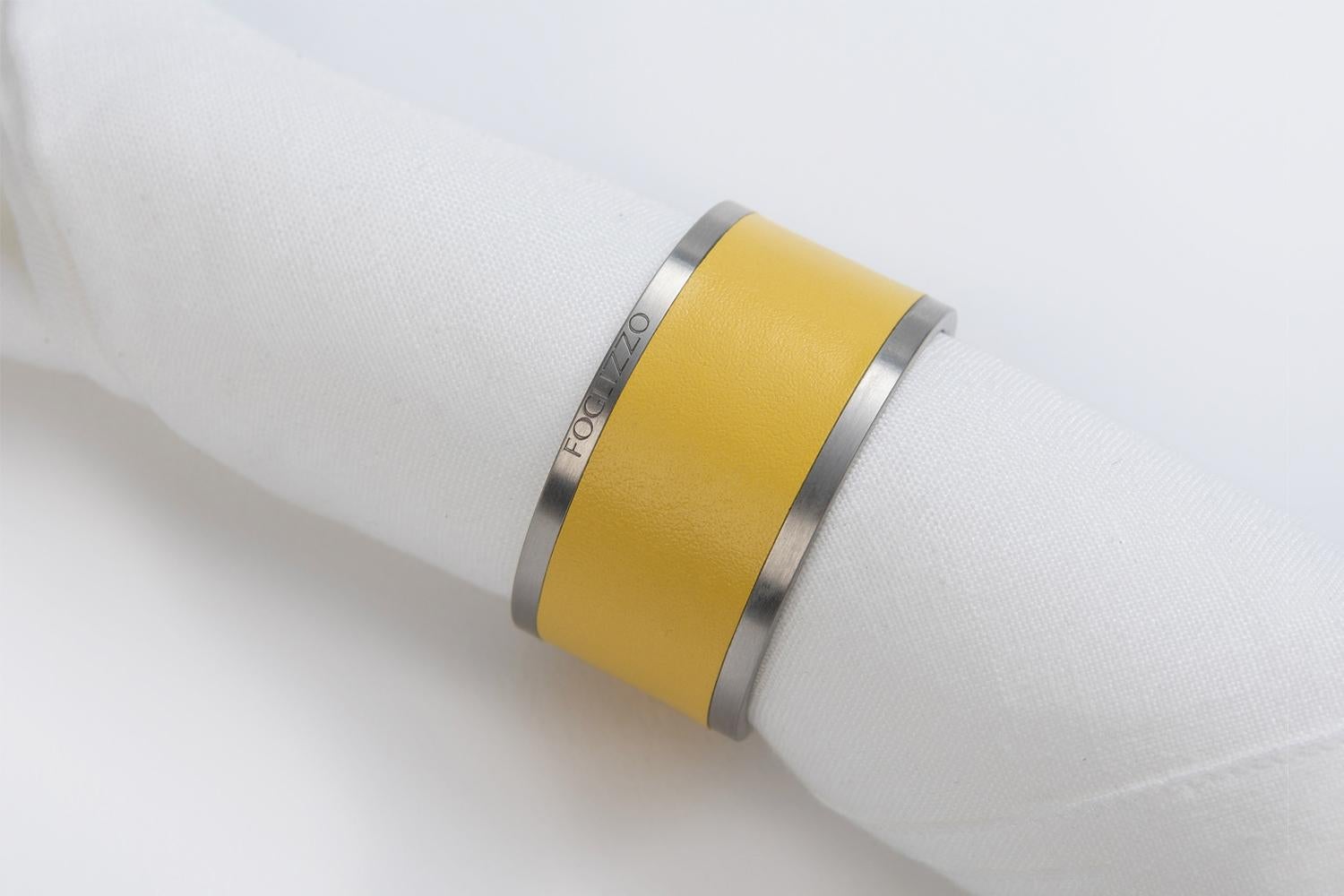 Il portatovagliolo dal design minimo dona un accento sorprendente su tavoli moderni o classici. La semplice silhouette è realizzata in acciaio inossidabile, parzialmente rivestita con esclusiva pelle Foglizzo.