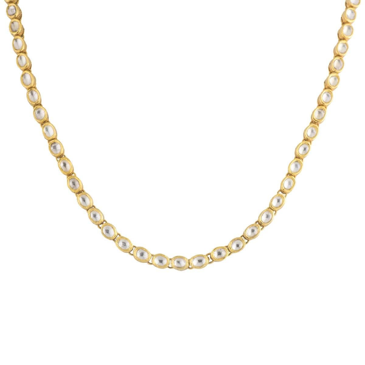 Simple and chic, this single strand reversible 18-karat with 24-karat yellow gold necklace can be layered or worn with a pendant. Intriguing handcrafted oval shaped bezel-settings with rock crystals set on the front.  Approximate rock crystal carat