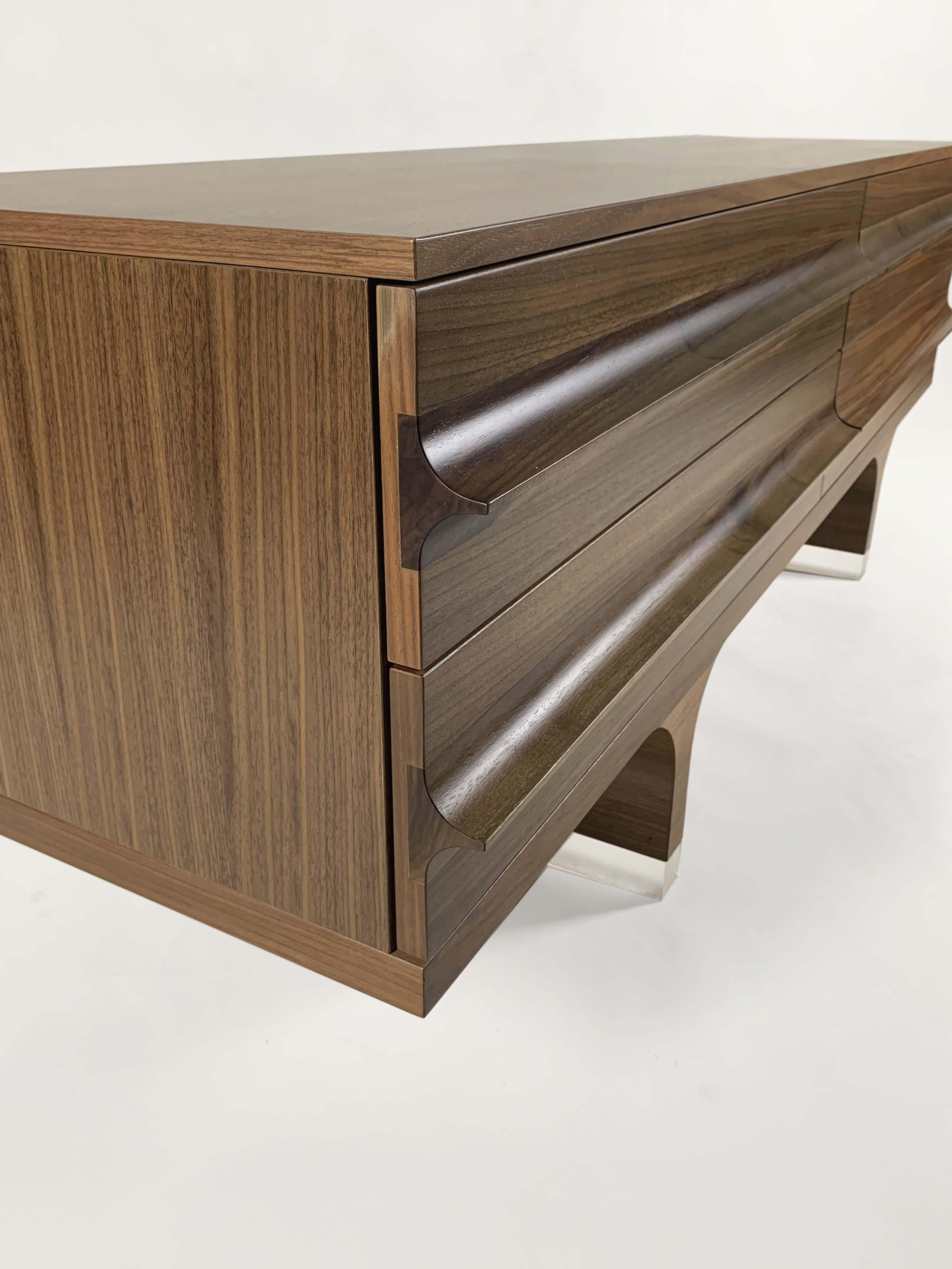 Disegnata da Franco Poli per Bernini nel 2003, la madia 0+1C appartiene a una raffinata collezione di arredi per il living, riconoscibile per le sue linee morbide e il design essenziale. L'elemento distintivo è l'elegante maniglia strutturale che
