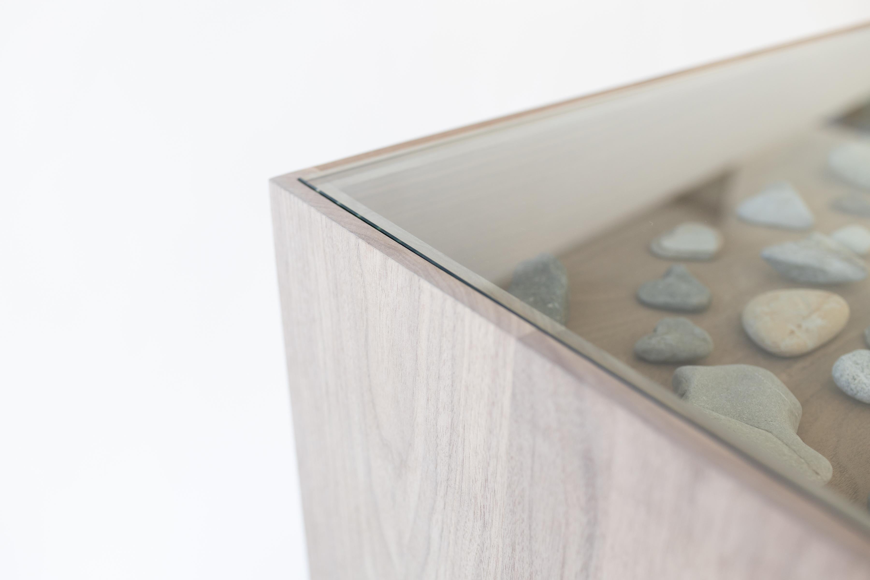 Fabricada en madera de nogal, la Consola Madigan presenta un marco sin teñir que resalta su belleza natural. Con un elegante panel de vista de cristal, ofrece un toque moderno a la vez que proporciona un espacio ideal para exponer recuerdos