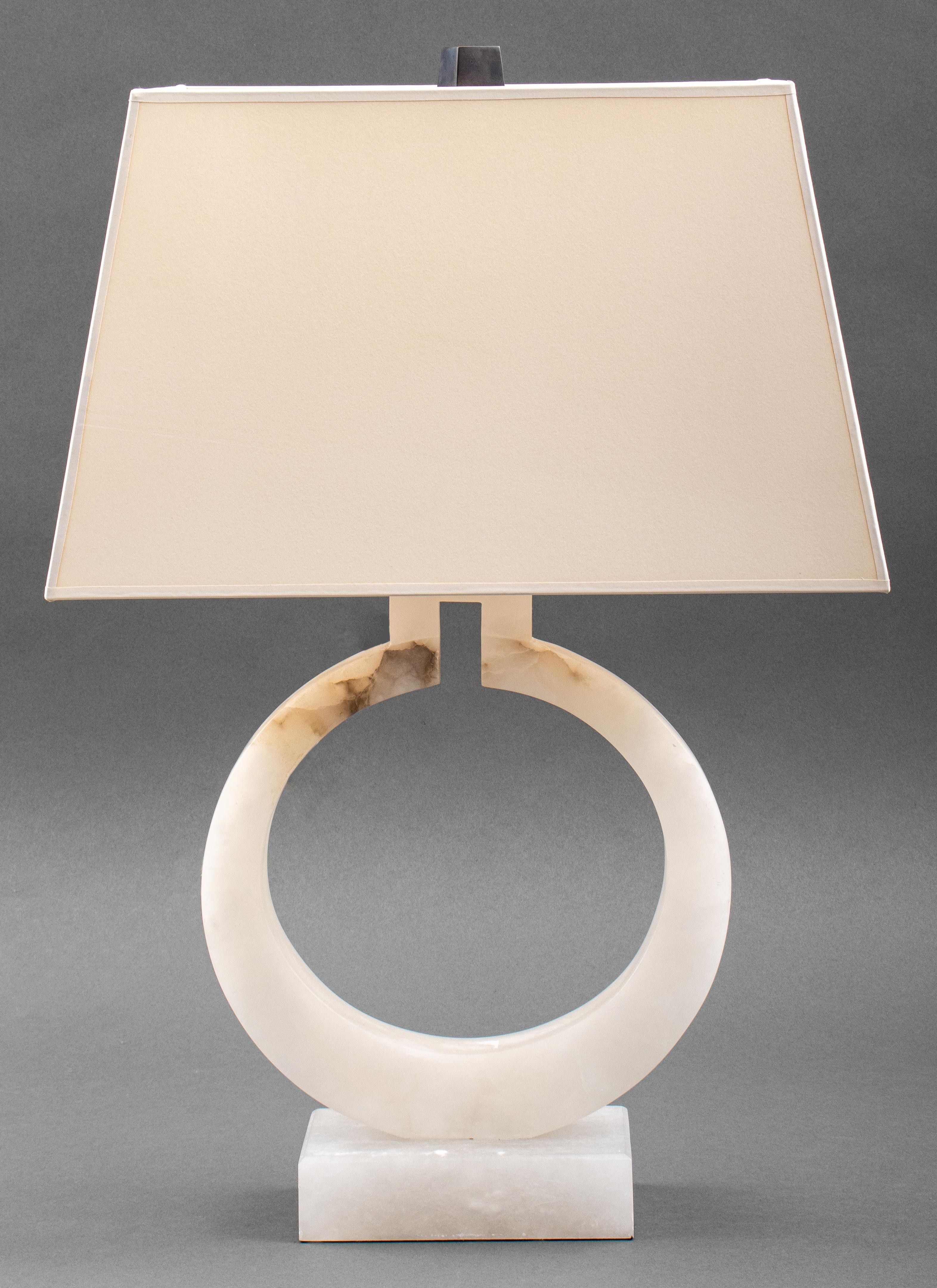 Madison alabaster table lamp of ring-form mounted on a slim rectangular base, fitted with a white lampshade and topped by a patinated bronze finial. 27