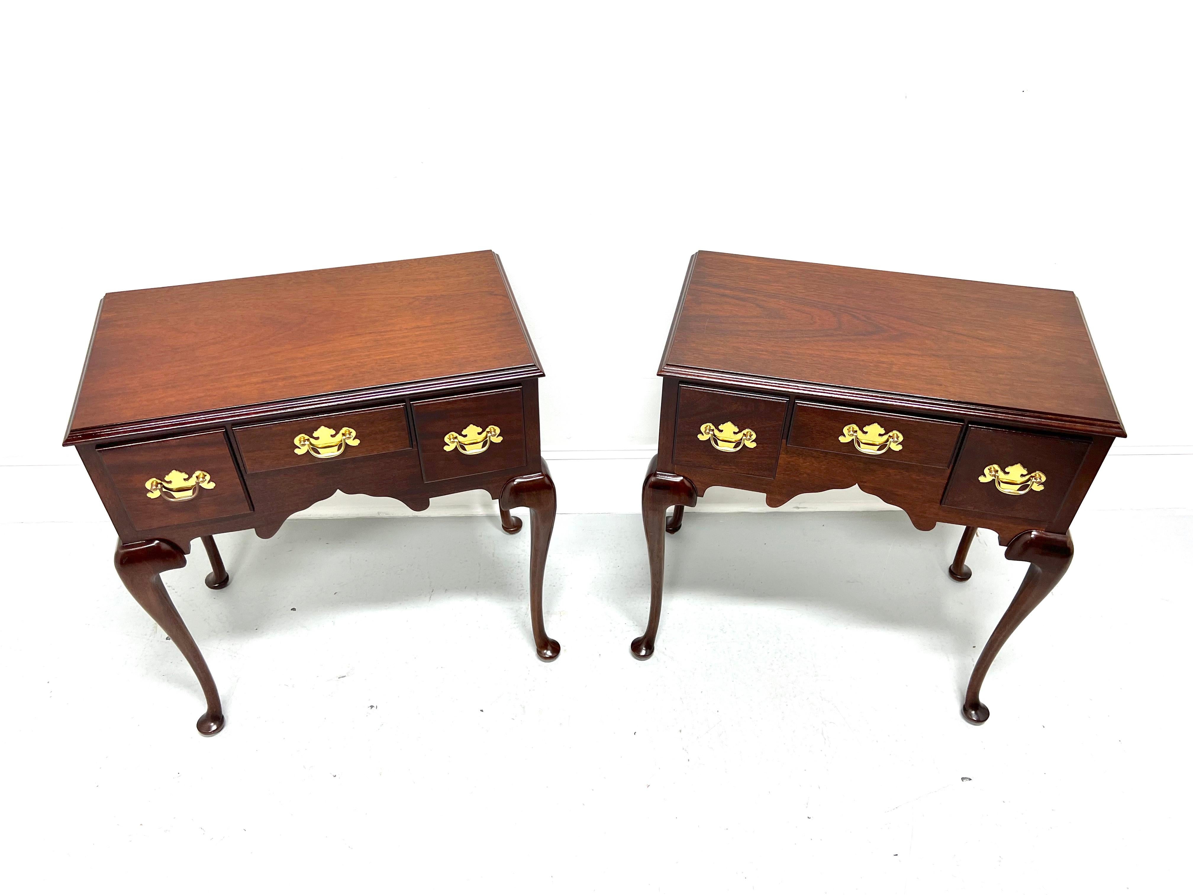 A pair of Queen Anne lowboy style bedside / side tables by Madison Square. Mahogany with brass hardware, ogee edge to top, carved apron, cabriole legs, and pad feet. Features three small drawers of dovetail construction. Made in Hanover,