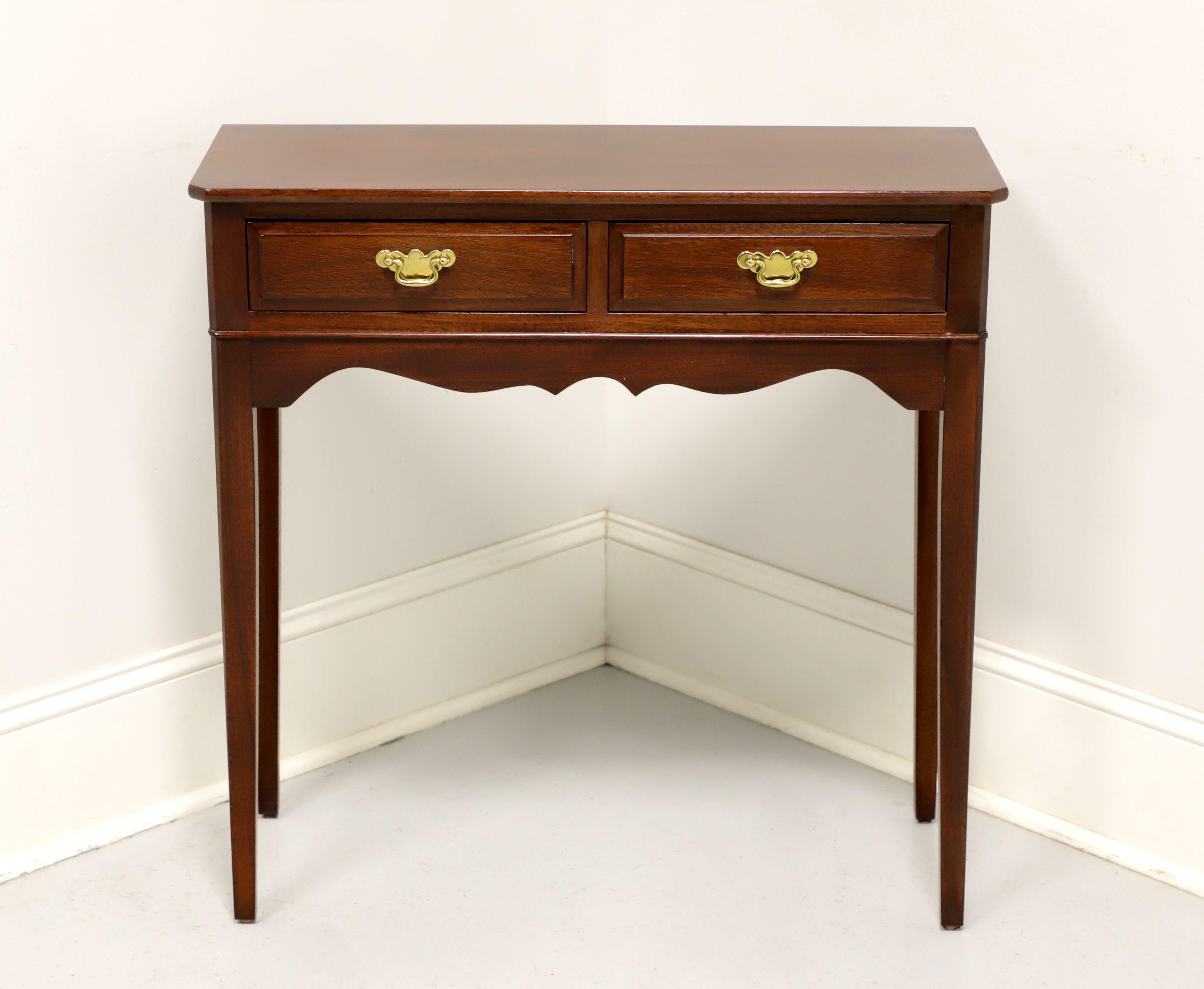 A Traditional style diminutive console table by Madison Square, of Hanover, Pennsylvania, USA. Mahogany with brass hardware, clipped corners, carved apron and tapered straight legs. Features two drawers of dovetail construction. Perfect size for