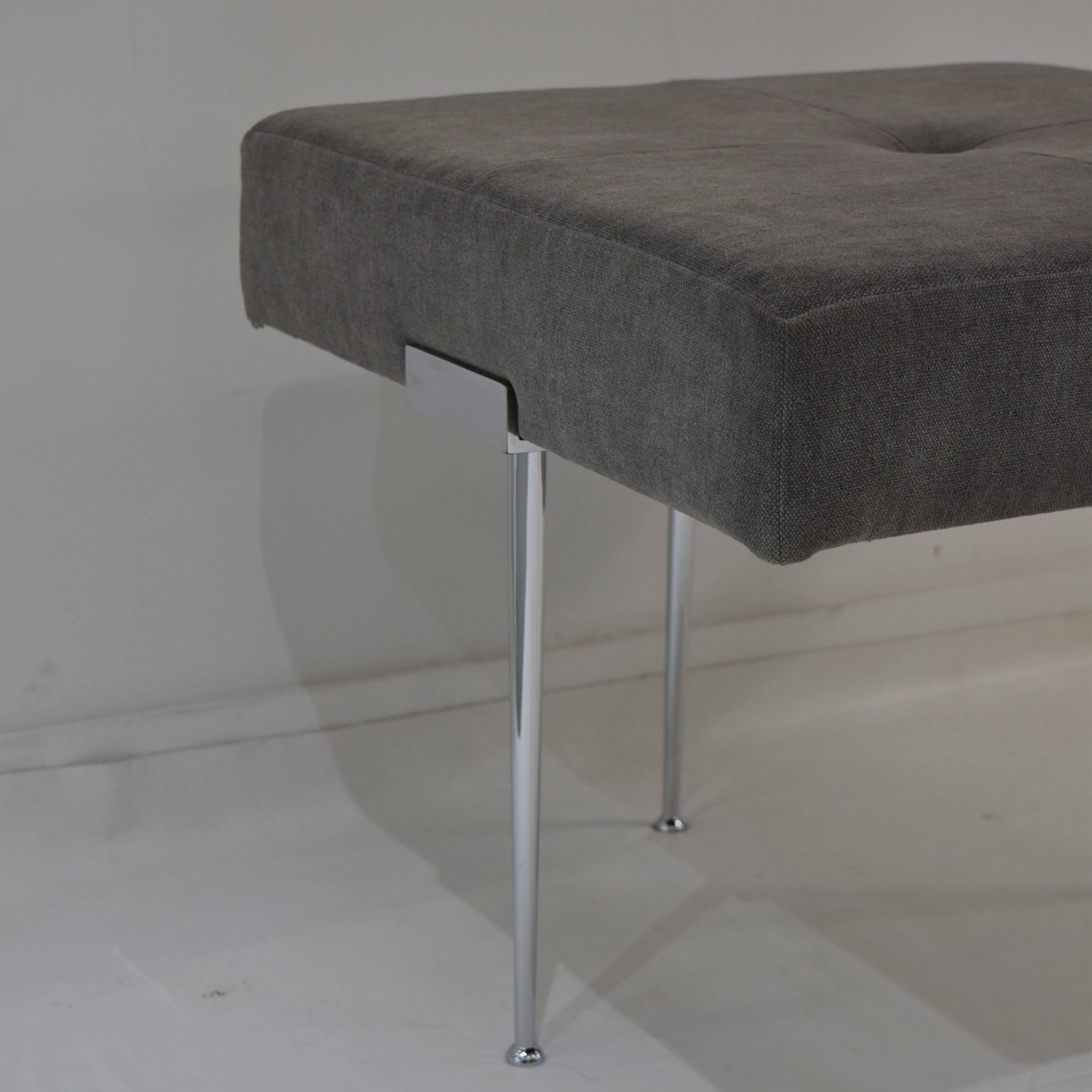 Our Madison square ottoman is designed by Irwin Feld Design for CF Modern and is covered in a tailored grey upholstery with four intersecting seams and button detail. The four hand cast and hand polished Madison legs are finished in chrome. Lead