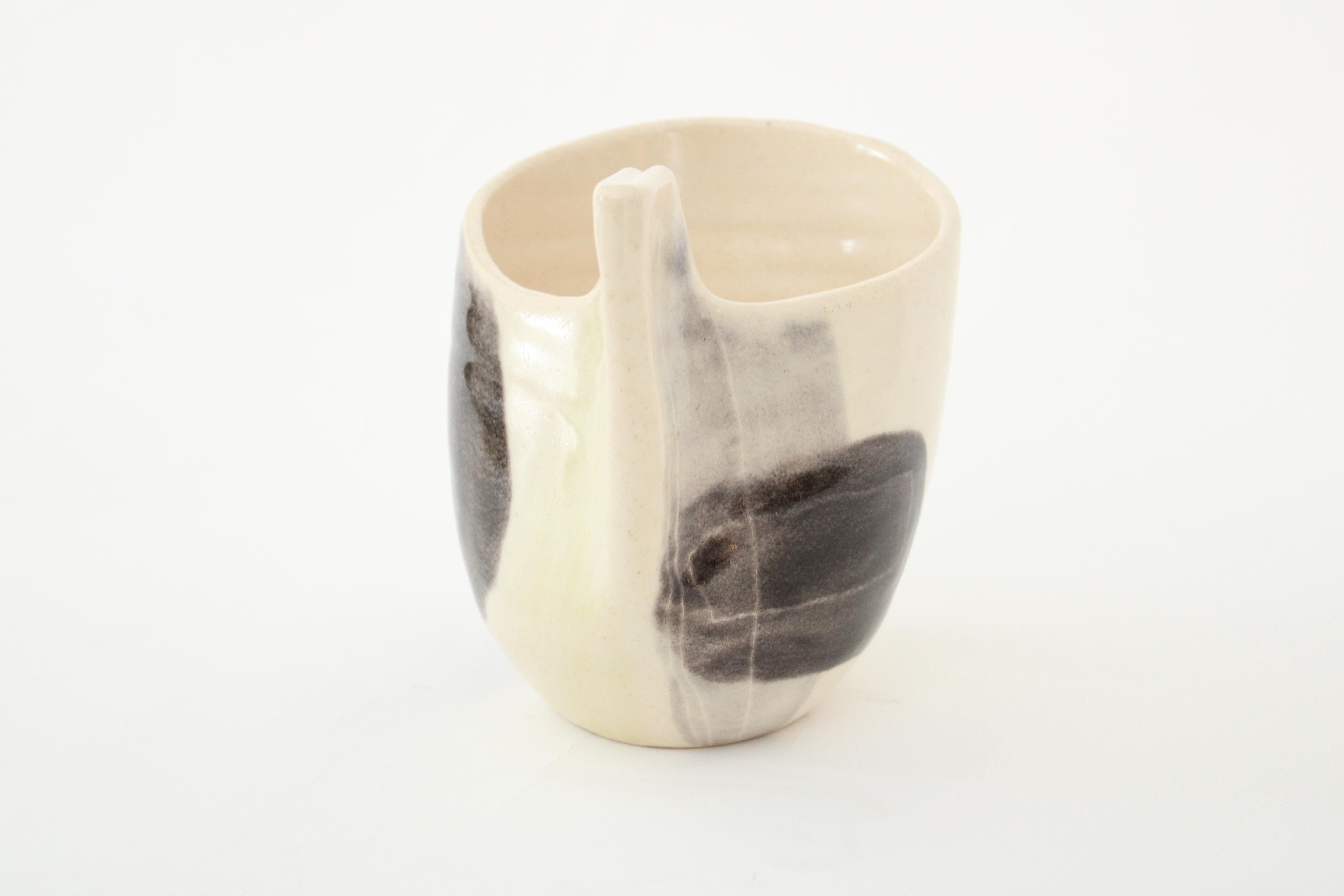 Mado Jolain 1921-2019 ceramic vase with cream black and white and touch of yellow abstract drawing and glaze on each surface and cream interior.
With a pinched handle, a very iconic gesture in her work. Signed MJ.
Iconic abstract drawings and