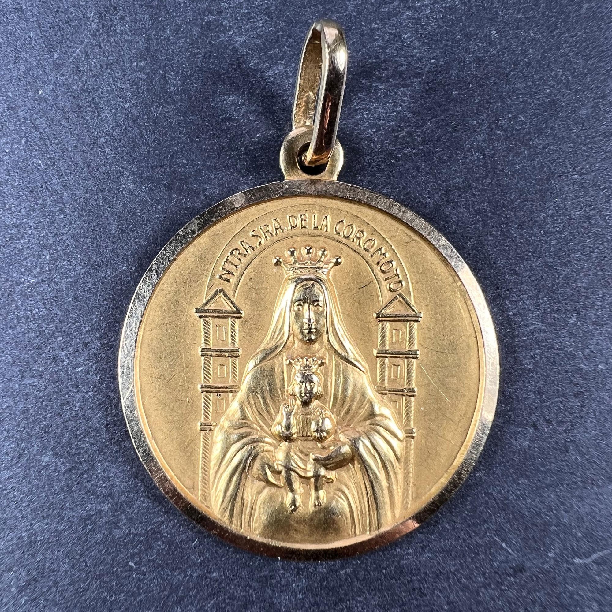 An 18 karat (18K) yellow gold pendant designed as a medal depicting the Madonna and Child in front of the Basilica of the National Shrine of our lady of Coromoto in Venezuela, topped by the phrase 'NTRA SRA DE LA COROMOTO' (Our Lady of Coromoto).