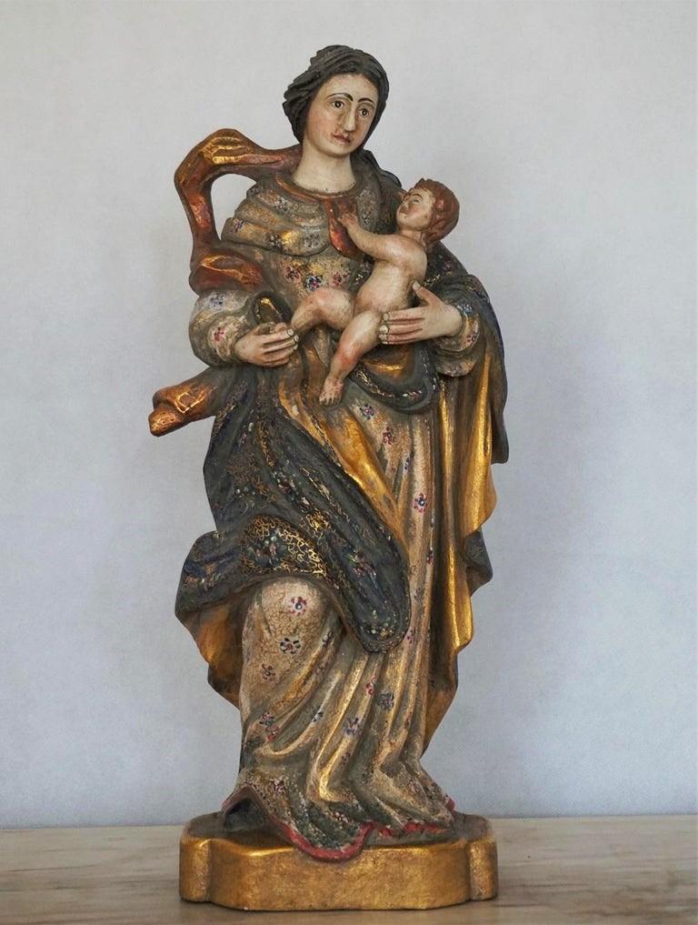 Holzskulptur, wunderschön geschnitzte Darstellung der Jungfrau Maria mit Jesuskind, vergoldet mit Blattgold und polychrom bemalt, Spanien, Mitte des 18. Jahrhunderts.
Diese fein handgeschnitzte Holzfigur auf einem schlichten Sockel aus demselben