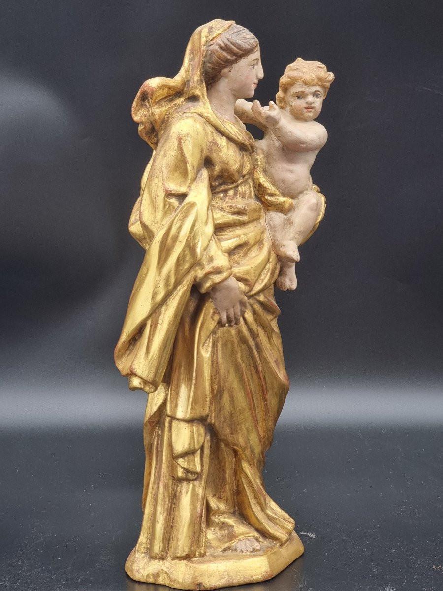 Escultura de madera que representa a la Virgen con el Niño, tallada a mano y posteriormente dorada con pan de oro y lacada. La obra, probablemente de madera de tilo, mide 38 cm de altura, 16,5 cm de anchura y 11 cm de profundidad. La Virgen está