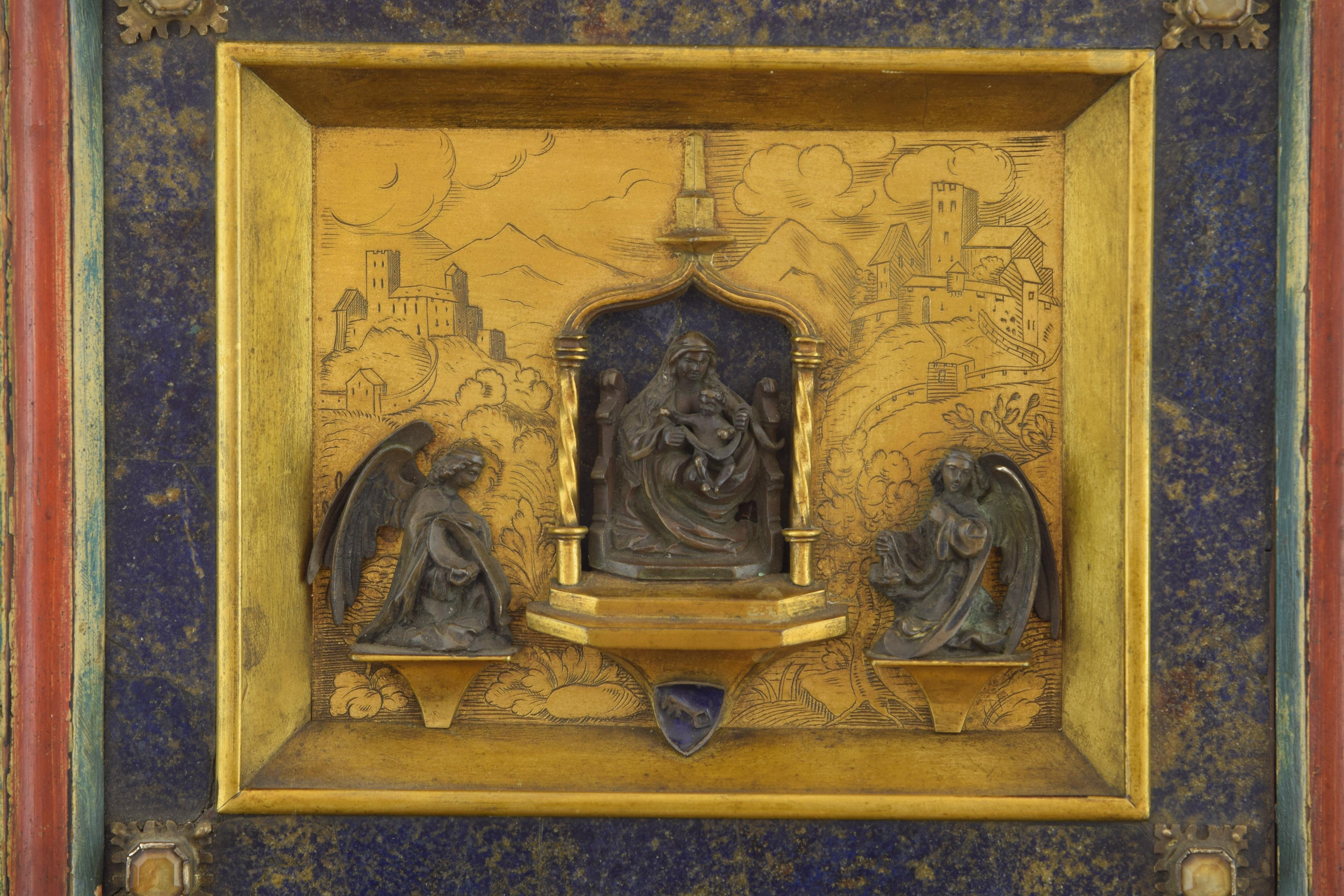 Bronze in its color and gold, lapis lazuli, rock crystal, enamel.
In the centre of the work is presented, enthroned, the figure of Mary, with a mantel (fireplace) on her shoulders and hair and holding on her knees the child, who appears addressing