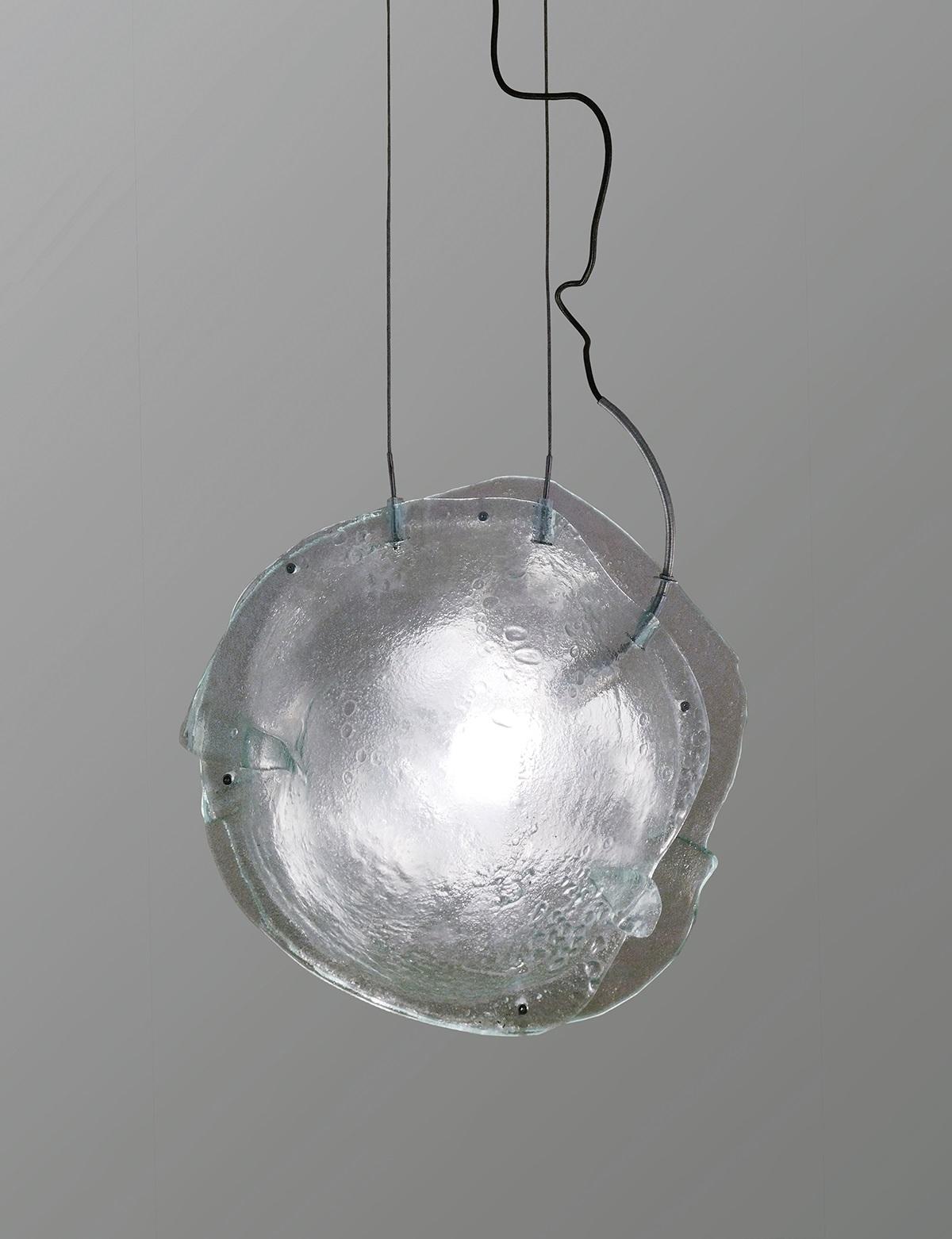 Lampada a sospensione Madreperla III di A. Moreno
Fatto a mano
Dimensioni: D 30 x L 52 x H 53 cm.
Materiali: Vetro.

Lampada da soffitto realizzata con i resti di vecchie finestre, modellate con un processo simile alla cremazione umana e sottoposte