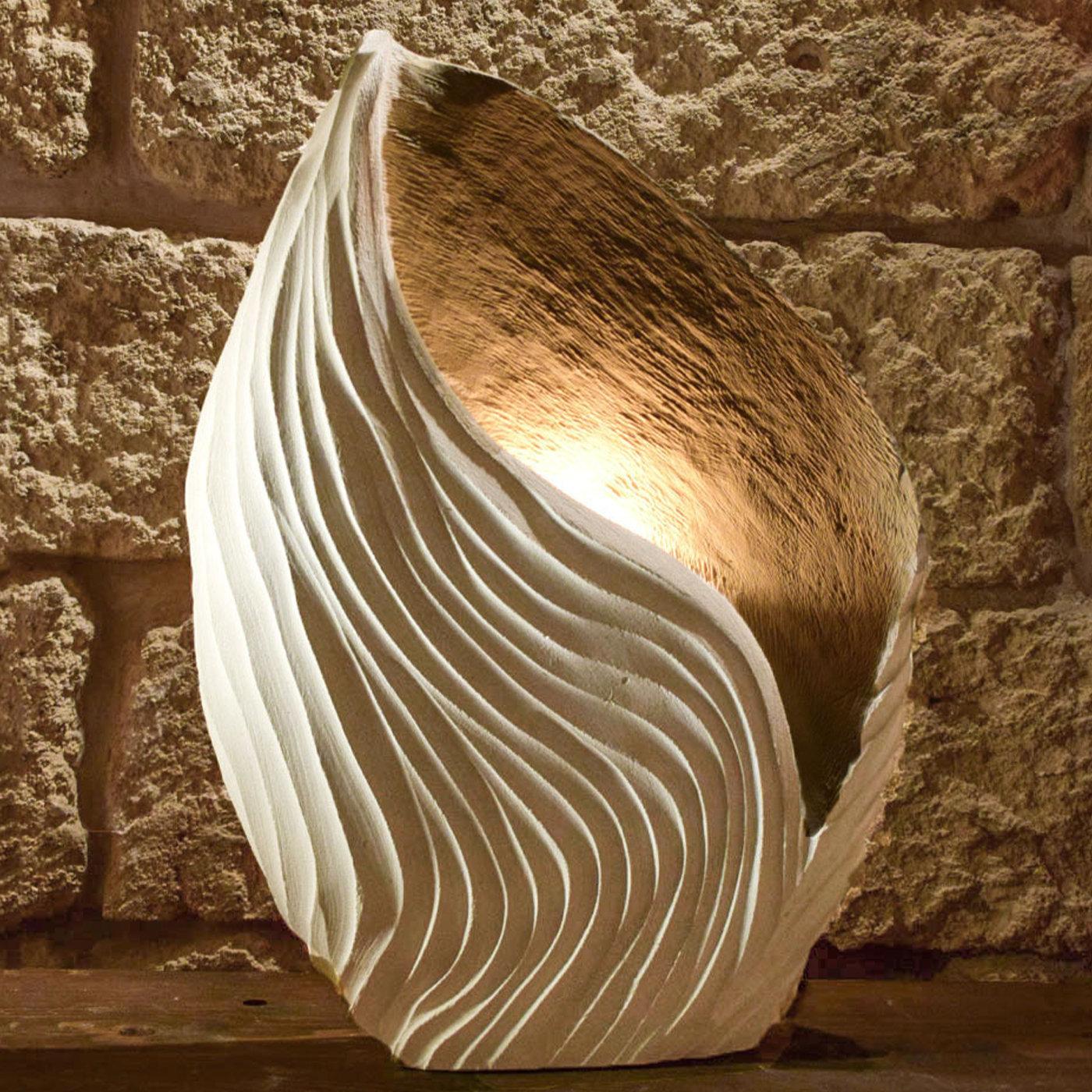 In parte scultura, in parte lampada, questa meravigliosa opera d'arte rende omaggio alla bellezza della natura utilizzando un materiale che ha un significato emotivo per l'artista. La pietra leccese è una pregiata pietra calcarea fossilifera che si