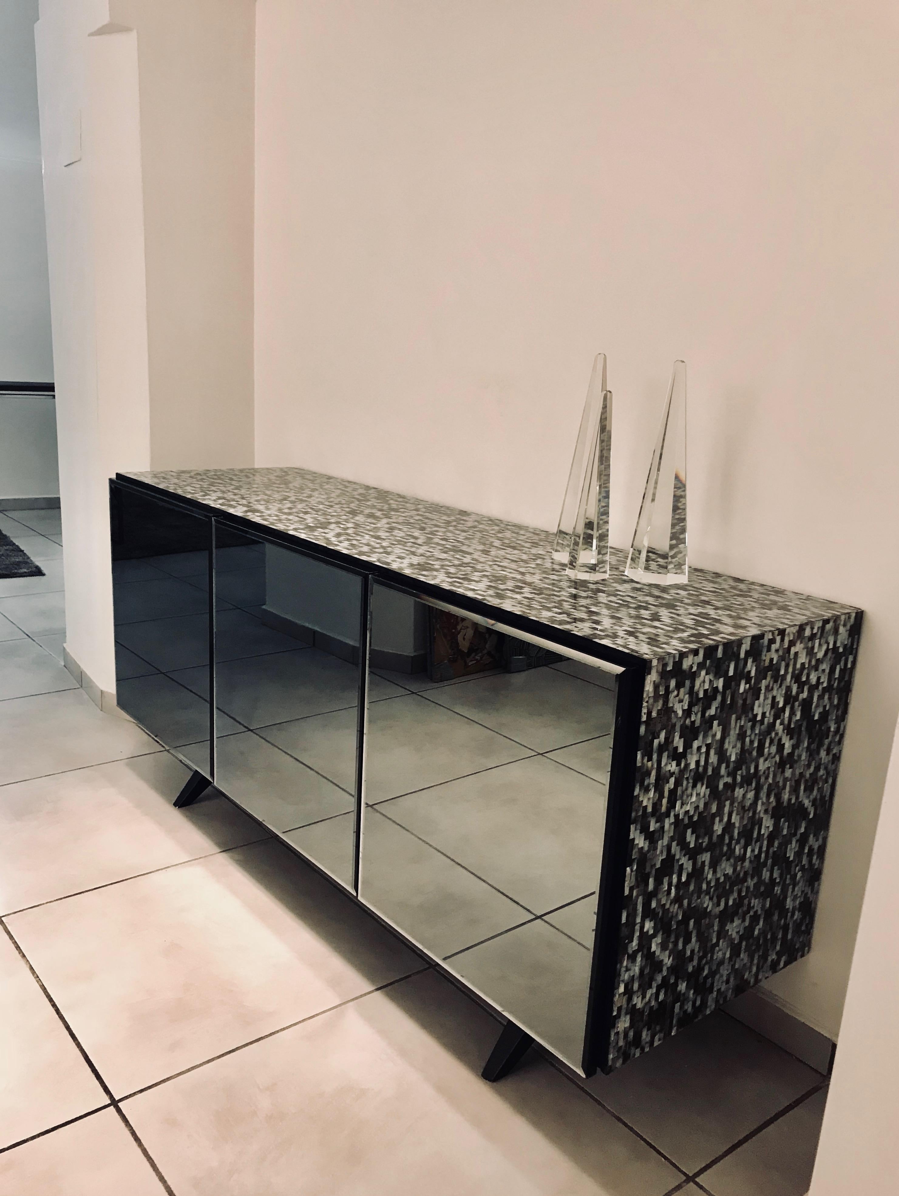 The 'Madrid' mother of pearl sideboard table is a contemporary high-end and beautifully composed piece.

Its design makes a bold statement with its captivating appearance - clad entirely in mesmerising mother of pearl and with smoked glass mirror