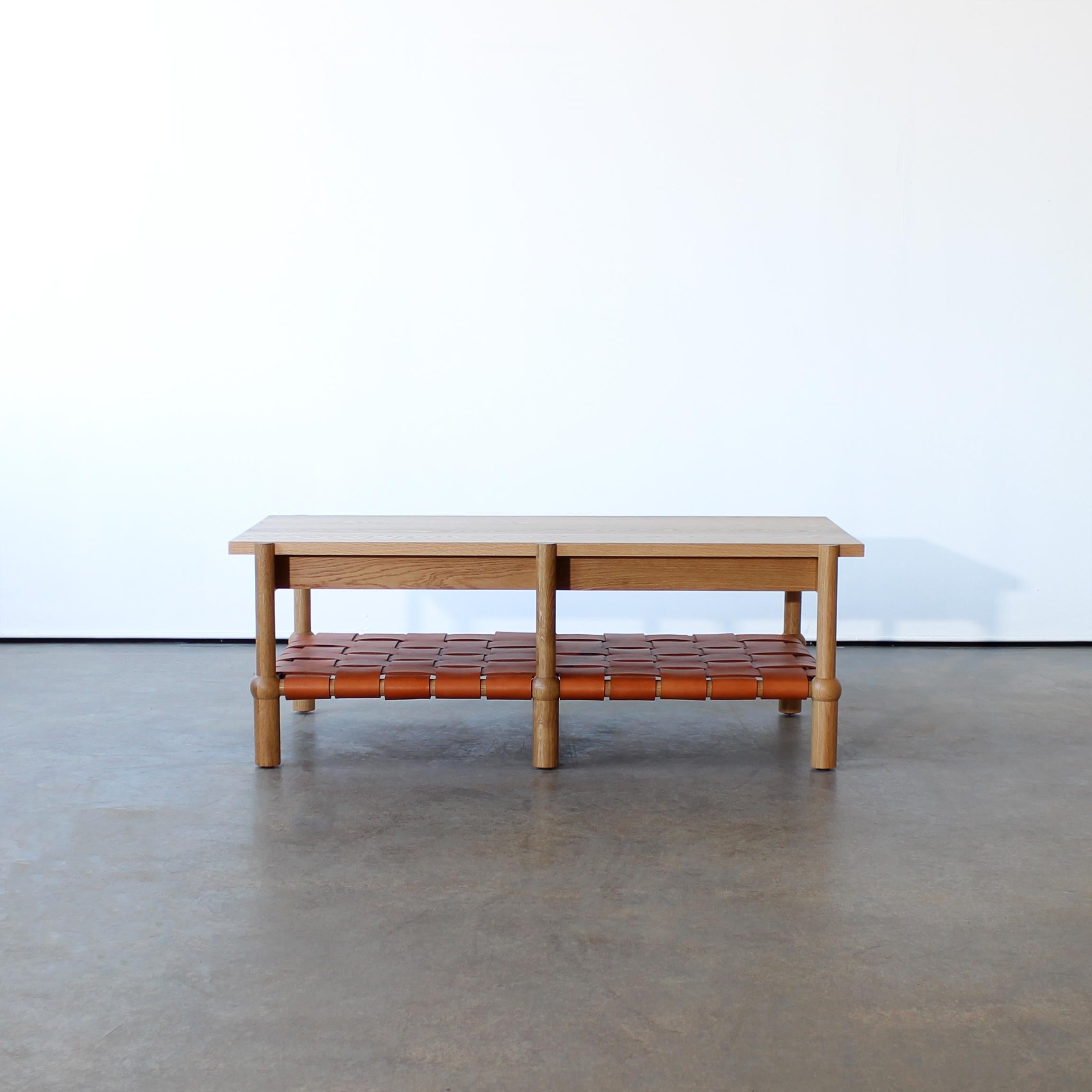 Mae coffee table 

Hand turned, solid wood legs and cross members / Solid wood top / Veg tan woven leather shelf / Customizations available.

Dimensions:
24” W x 48” L x 17” H

Customizations Available.