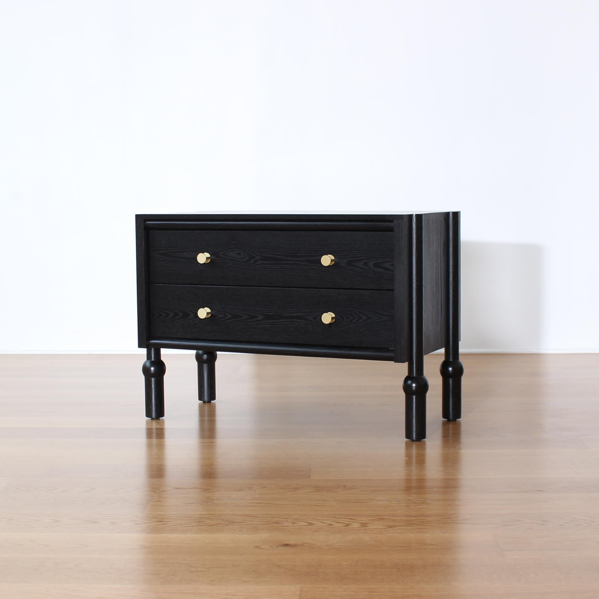 Mae Nightstand by Crump and Kwash 

Solid wood frame / hand turned legs / blackened finish / solid brass pulls / dovetailed solid wood drawer boxes / premium, full extension, soft close drawer slides

Customizations and other finishes available.