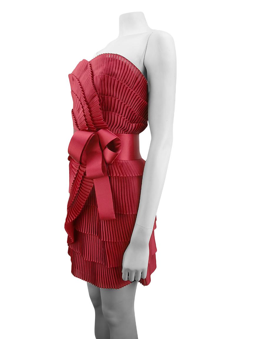 Originale abito a pieghe rosso Marchesa Notte in tessuto sintetico con dettagli in seta.
Presenta un design senza spalline, pieghe su tutta la lunghezza, una fascia di seta con fiocco in vita e una chiusura a zip sul retro. 

 Taglia EU 38 - US