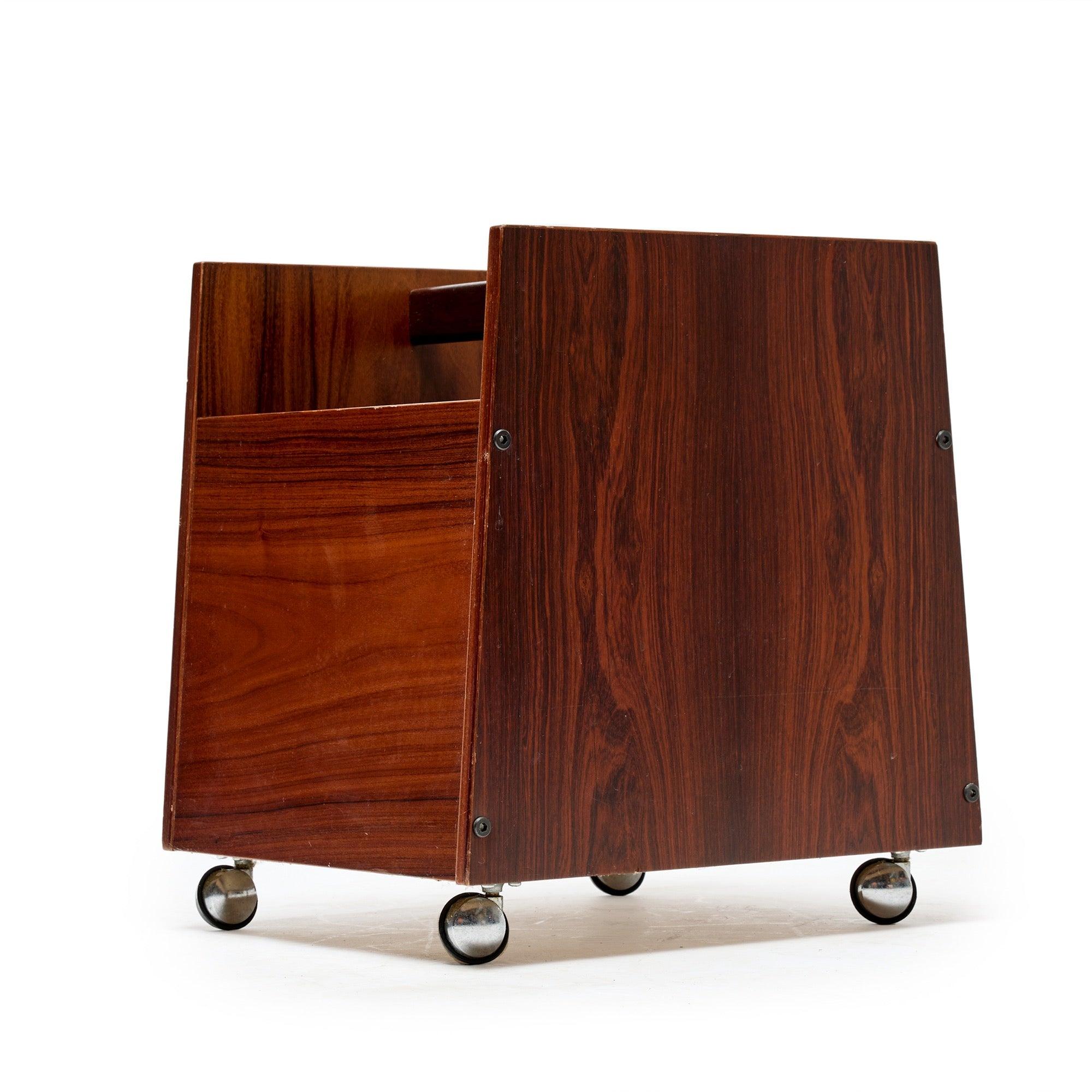 A rolling rosewood magazine caddy on four swivel casters with three divided compartments and a handle for ease of movement.