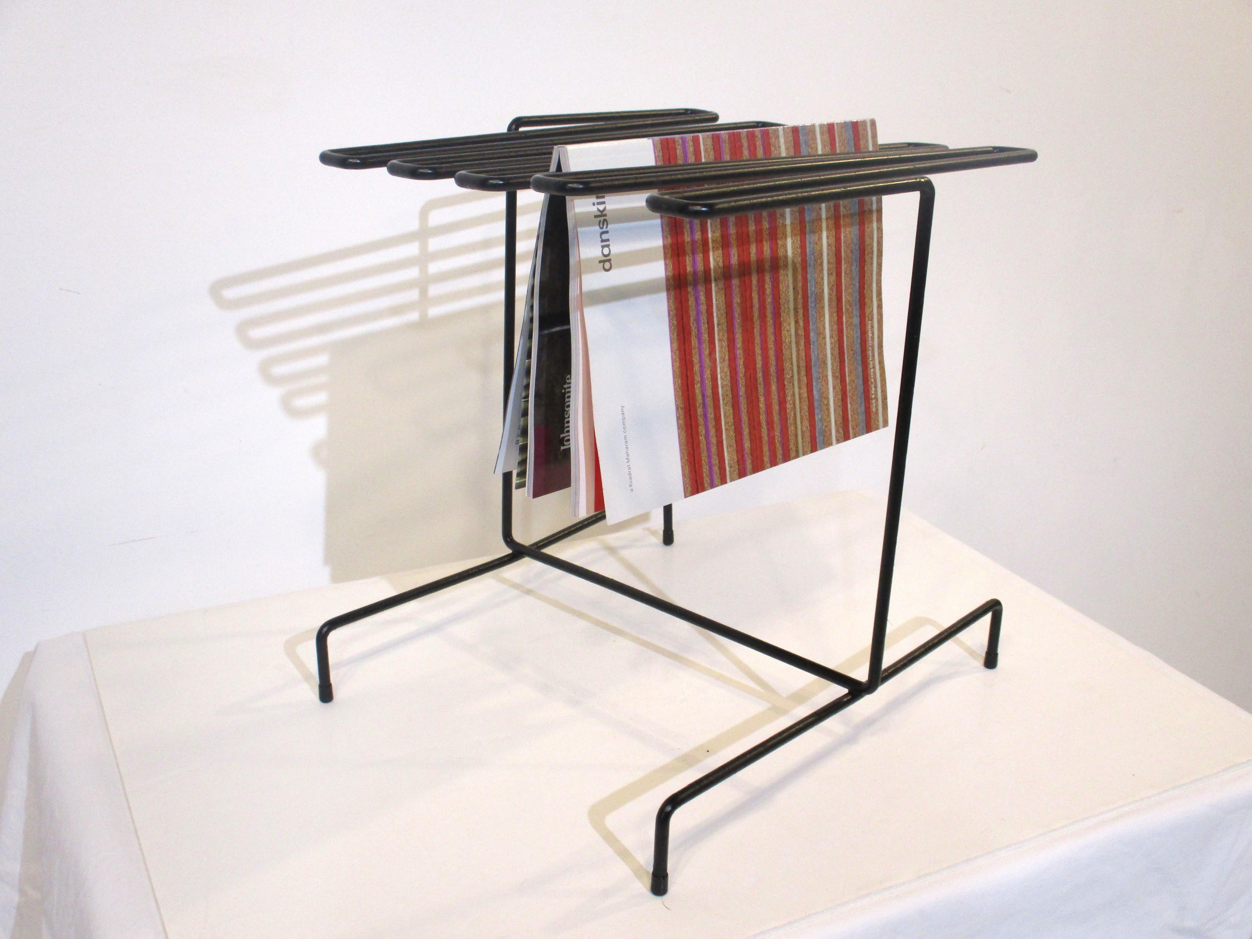 A sculptural satin black metal magazine, newspaper rack with nine hanging rods. Rubber feet are on the base to protect your floor and for stability designed and manufactured in the manner of Tony Paul, a simple form that is very practical.