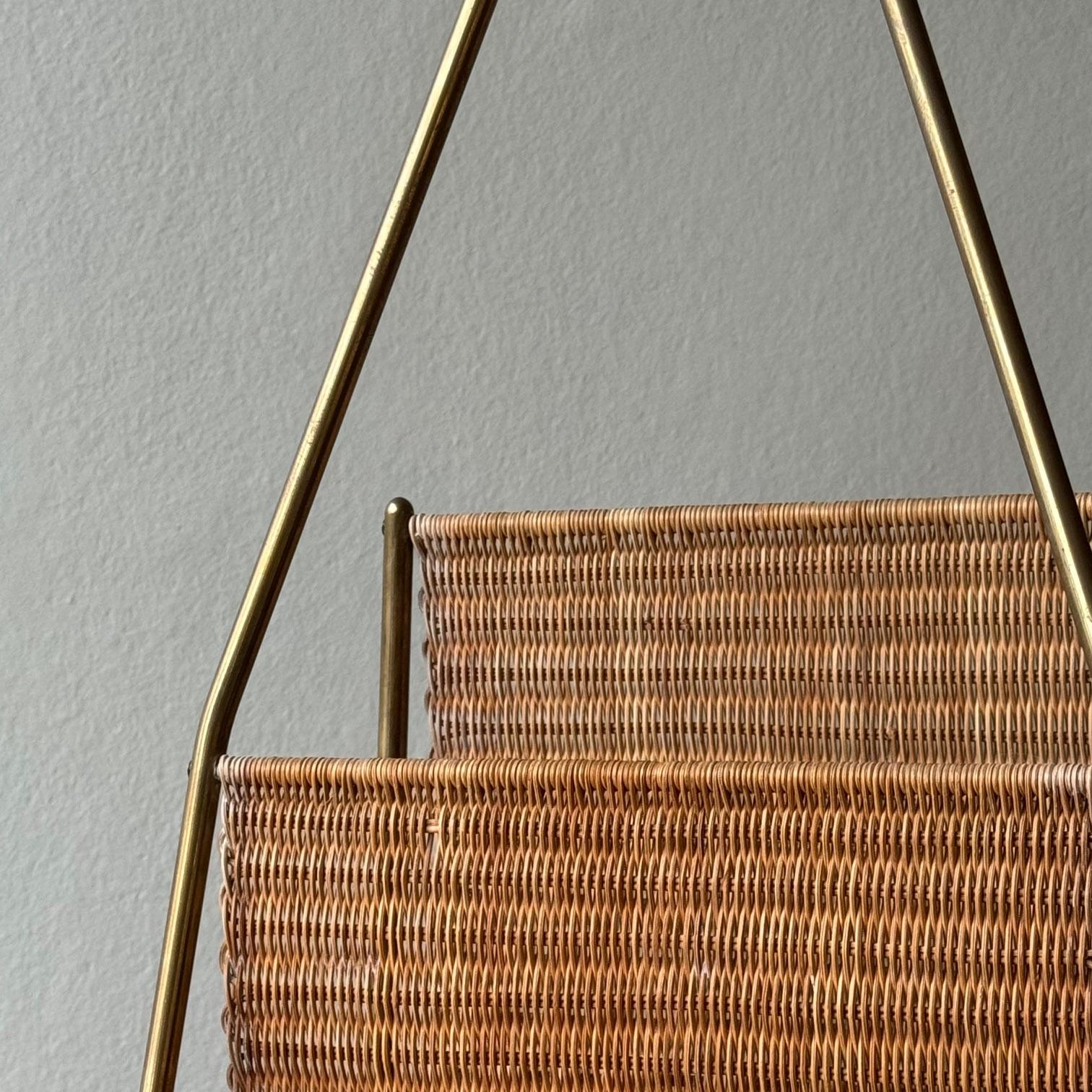 A wicker magazine rack designed by Carl Auböck II and made by the Carl Auböck workshop during the 1950s. The beautifully patinated frame of this brass magazine rack supports a tightly woven wicker sling large enough to hold a handful of magazines,