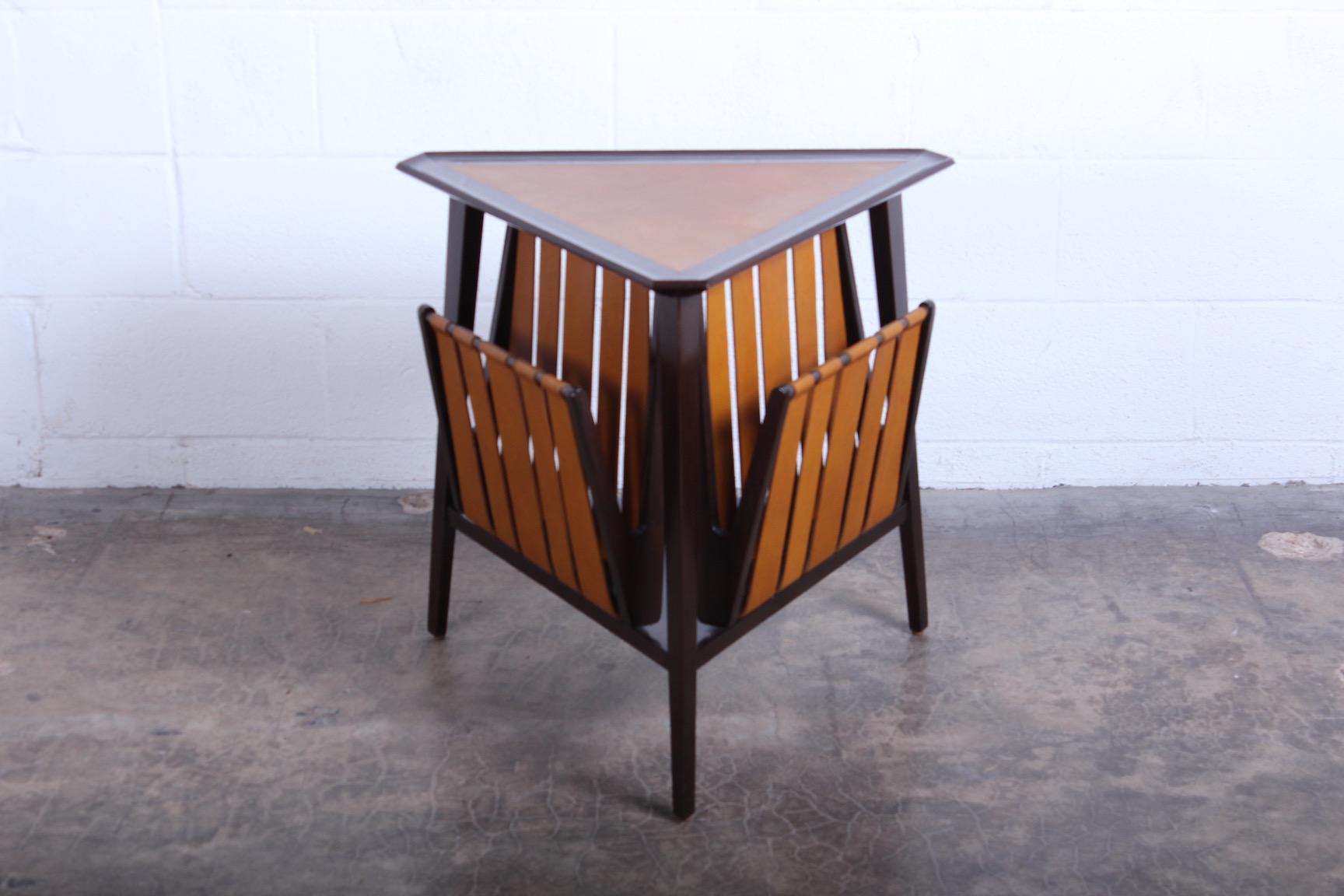 A triangular ash magazine table with inset leather top and leather straps. Designed by Edward Wormley for Dunbar.