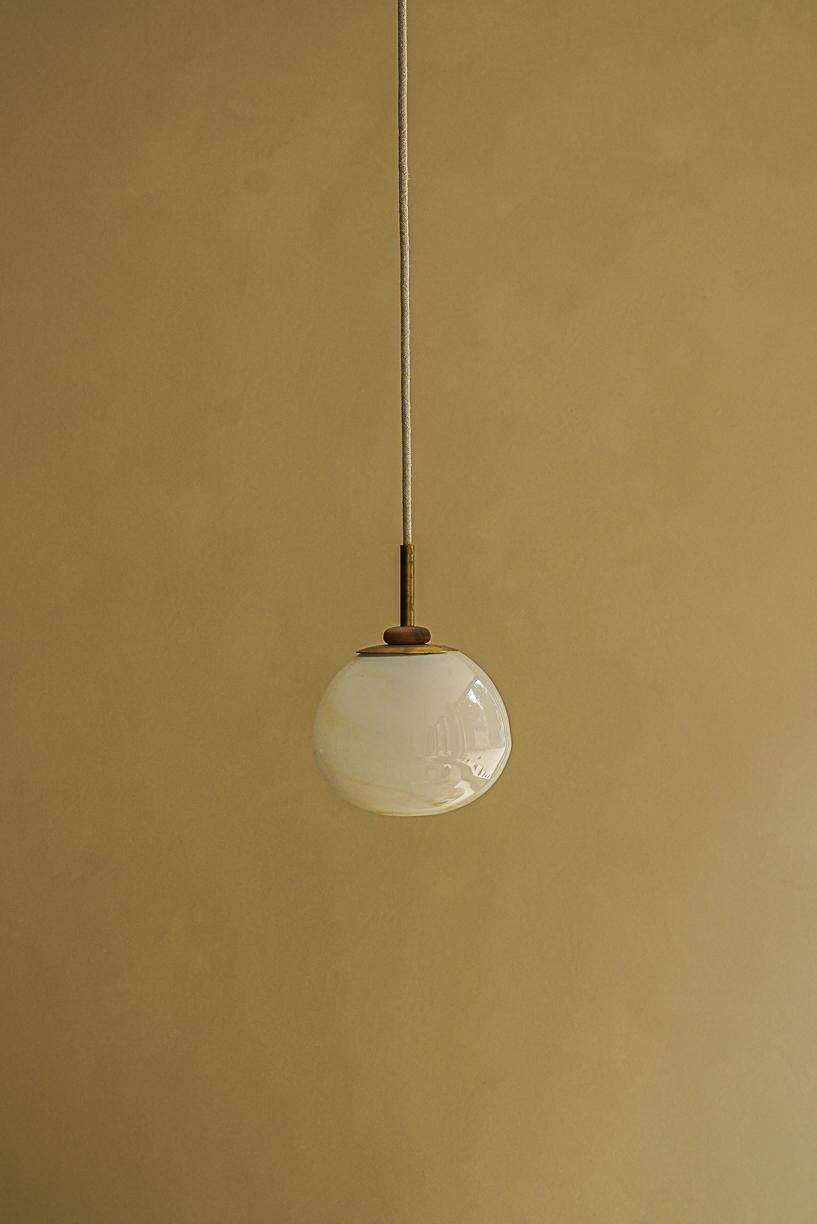 Magena I Pending Lamp by La Lune
Dimensions: Ø 15 x H 13 cm. 
Materials: Blown glass, linen cable, brass piece and turned wood ring.

Produced in France. Custom sizes available. Also available in different shapes. Please contact us.

La Lune is
