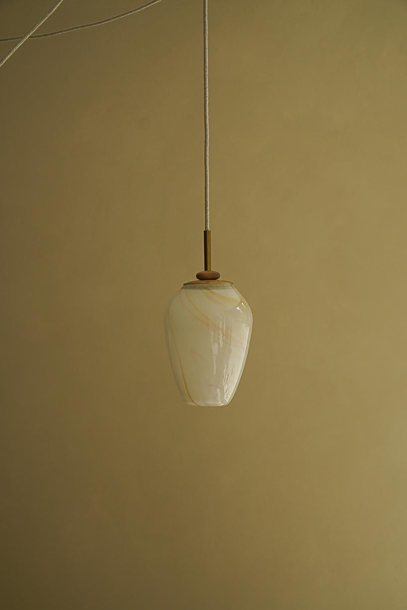 Magena III Pending Lamp by La Lune
Dimensions: Ø 16 x H 22 cm. 
Materials: Blown glass, linen cable, brass piece and turned wood ring.

Produced in France. Custom sizes available. Also available in different shapes. Please contact us.

La Lune is
