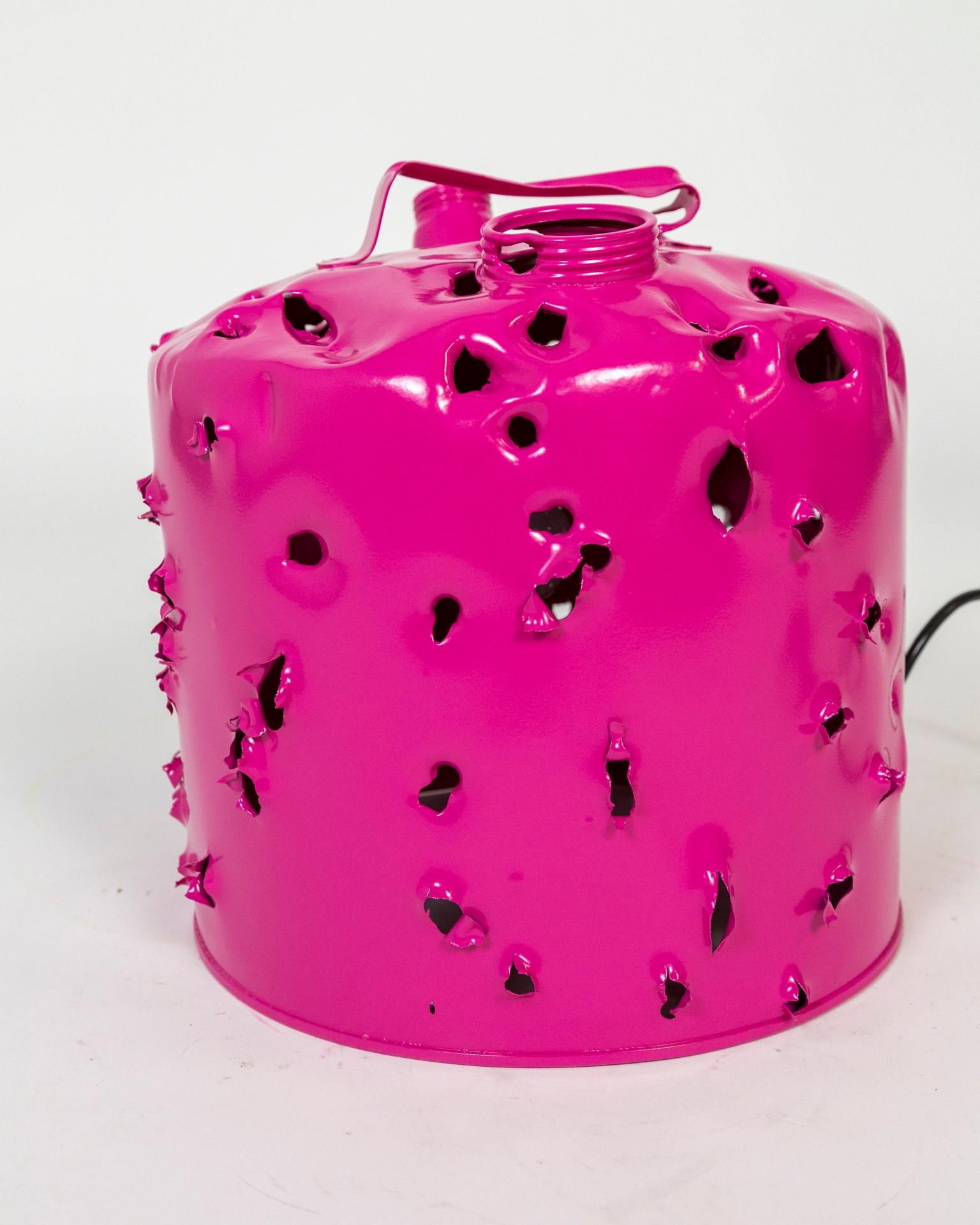 This antique metal gas can was shot with bullets, powder coated and wired as a lamp to become a bold work of art made Charles Linder. He has been making artwork out of bullet-riddled objects for over 30 years. The light coming through the holes has