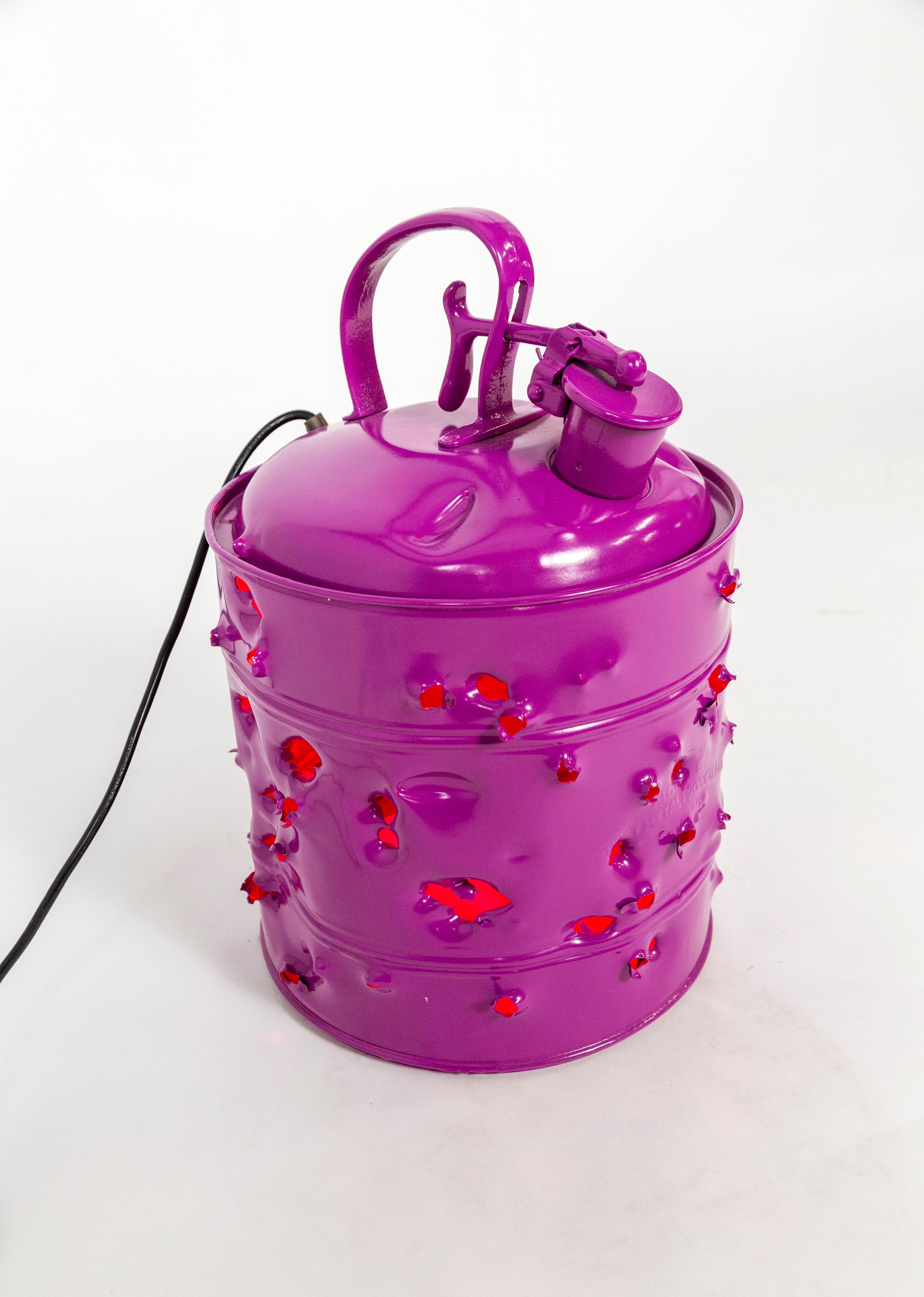 This powder coated, metal gas can is a bold art object by Charles Linder, who has been making artwork out of bullet-riddled objects for over 30 years. It can be used as a pendant light or as a lamp. Seen here lit with a red light bulb. We also have
