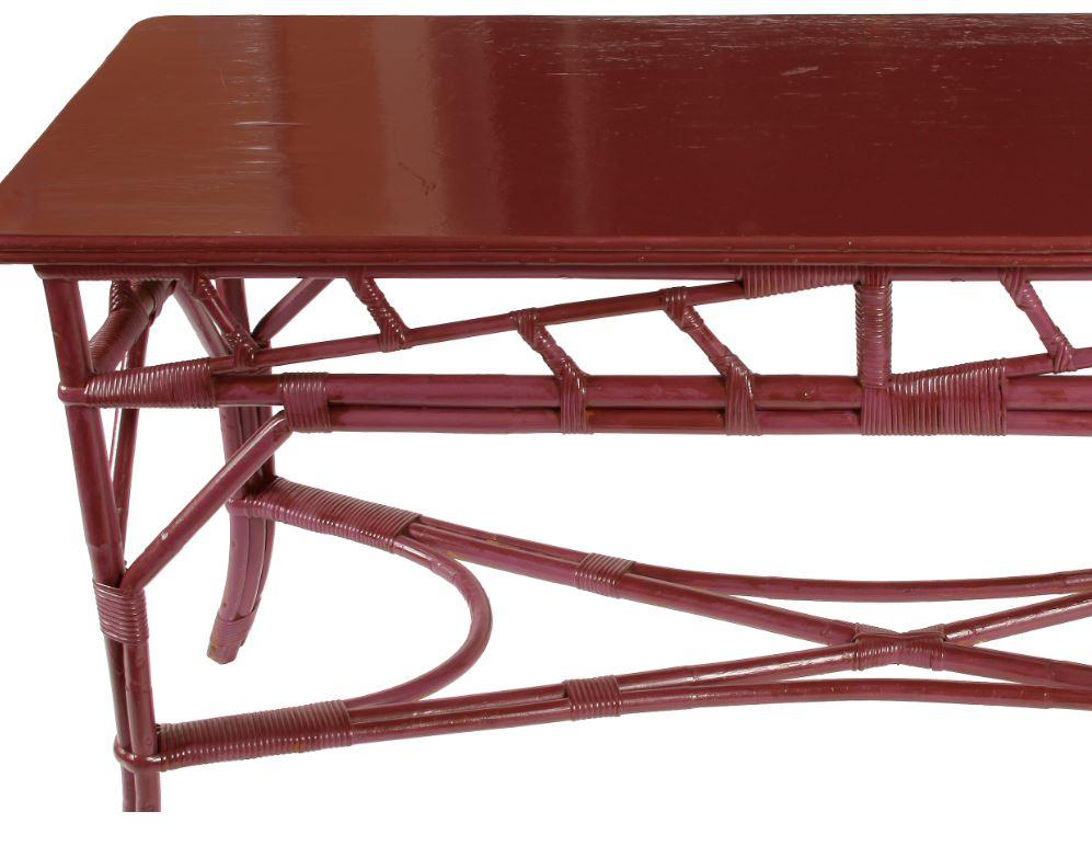 Rattan console painted striking shade of magenta. Bamboo fretwork design and X-shaped stretcher.