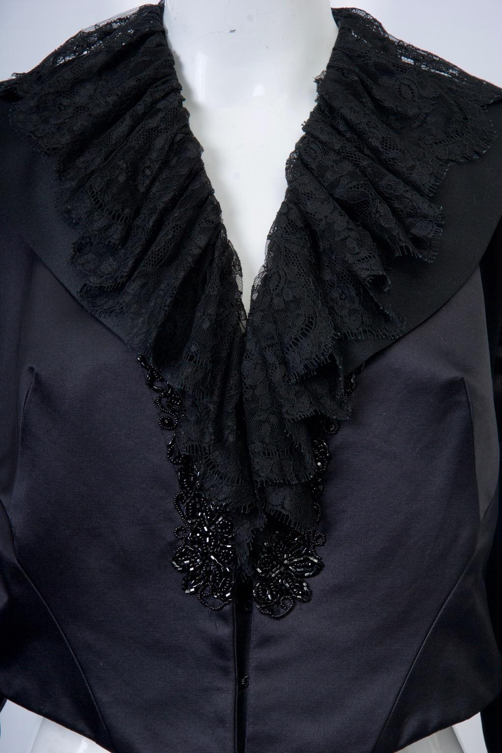 Esteemed contemporary designer Maggie Norris often uses historical references for her couture creations. Here we have a short, Edwardian-influenced evening jacket in black satin featuring black lace ruffle at the v-neck double collar and at the slit
