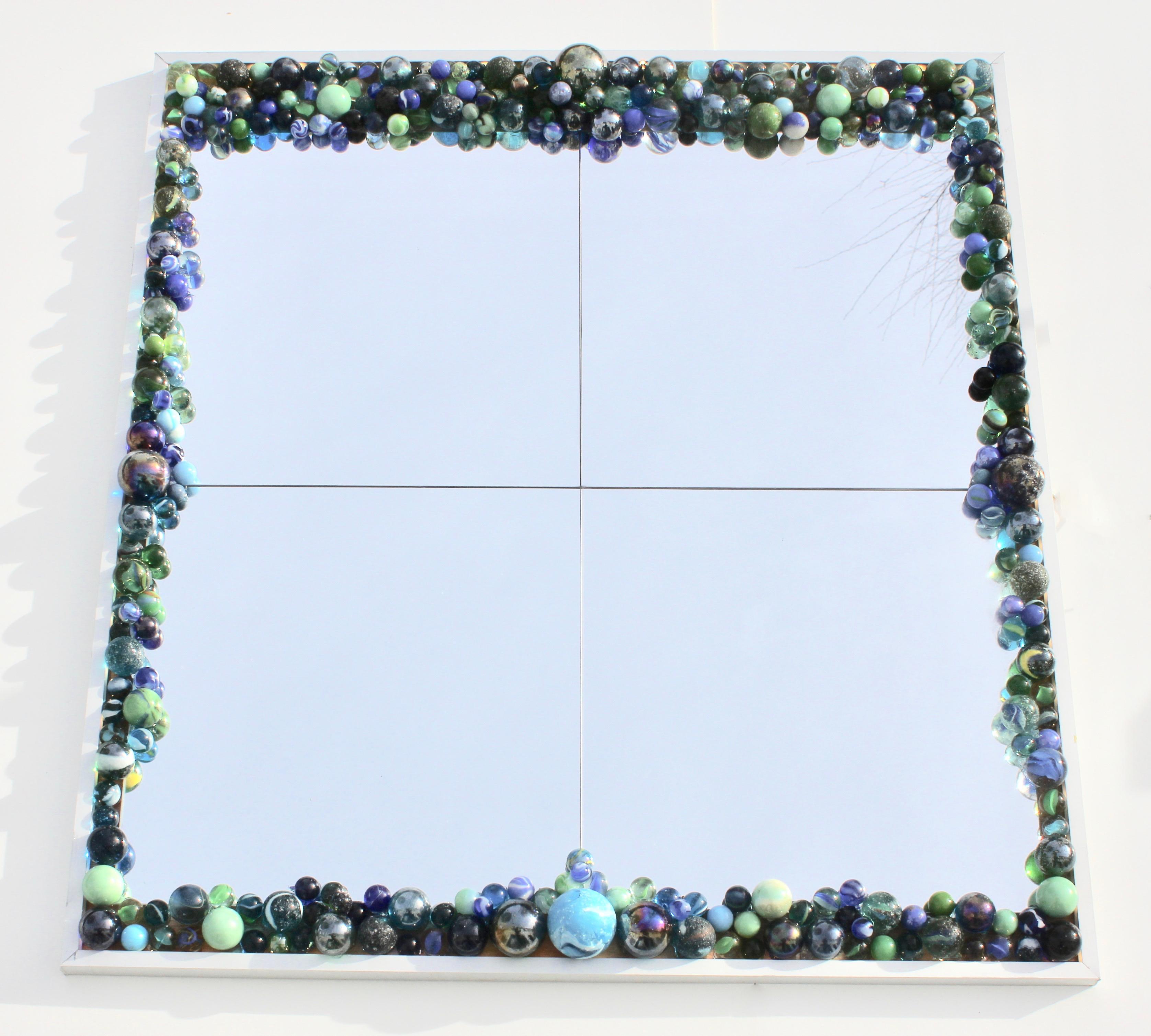 This stylish wall mirror has an LED light in the aluminum frame which illuminates the border of blue and green marbles. The impact and colors change dramatically according to the ambient (direction of sun) light and in the evening, the illuminated