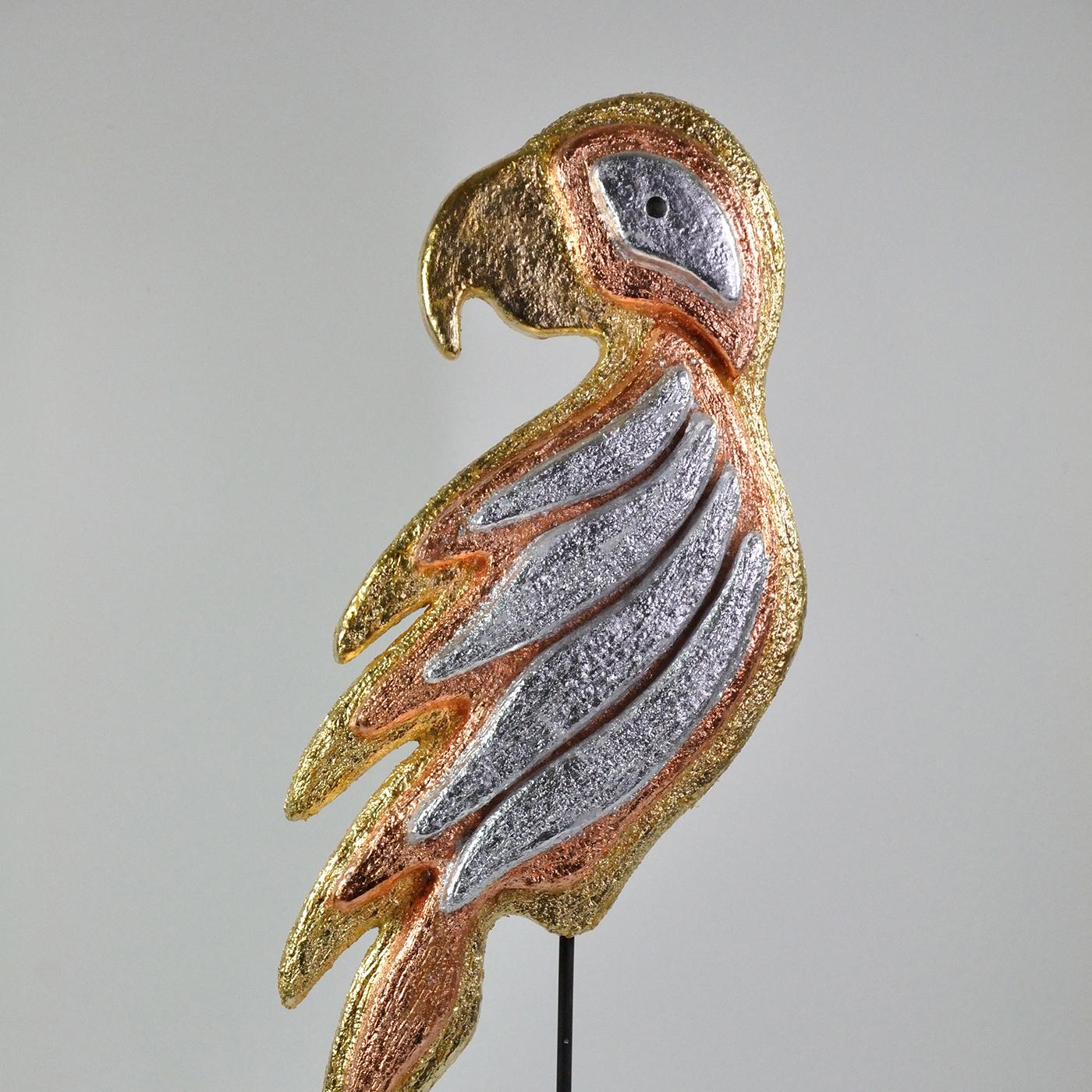 Diese zoomorphe Skulptur in Form eines mehrfarbigen Papageis, die exotische Atmosphären heraufbeschwört, ist eine gekonnte Demonstration von Handwerkskunst, angereichert mit einer Kombination aus Silber-, Gold- und Kupferblättern, die ihr eine