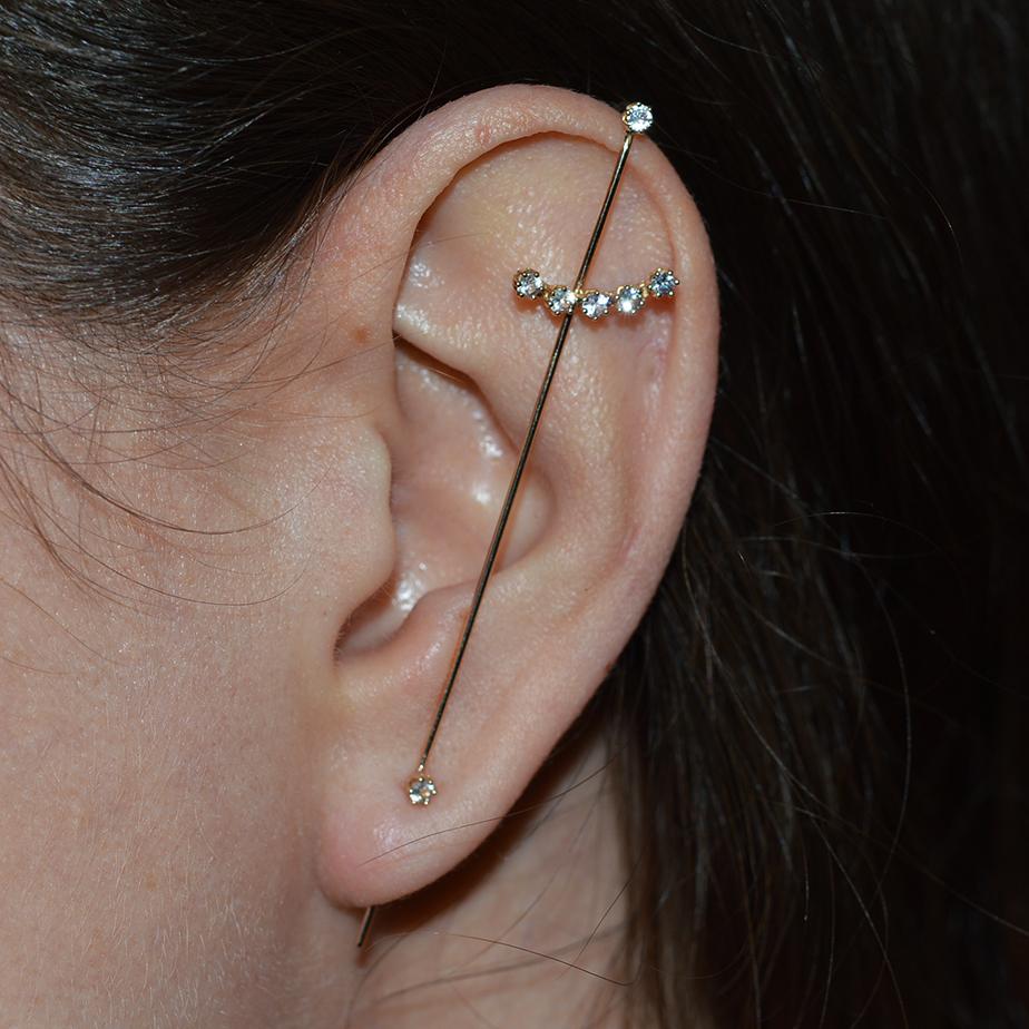 Der Magic Wand Needle Ohrring besteht aus einem nadelförmigen Goldstab, der mit einem zarten Bogen aus Diamanten und zwei einzelnen Diamanten verziert ist. Dieser Nadel-Ohrring bietet einen einzigartigen Look, ohne dass mehrere Piercings
