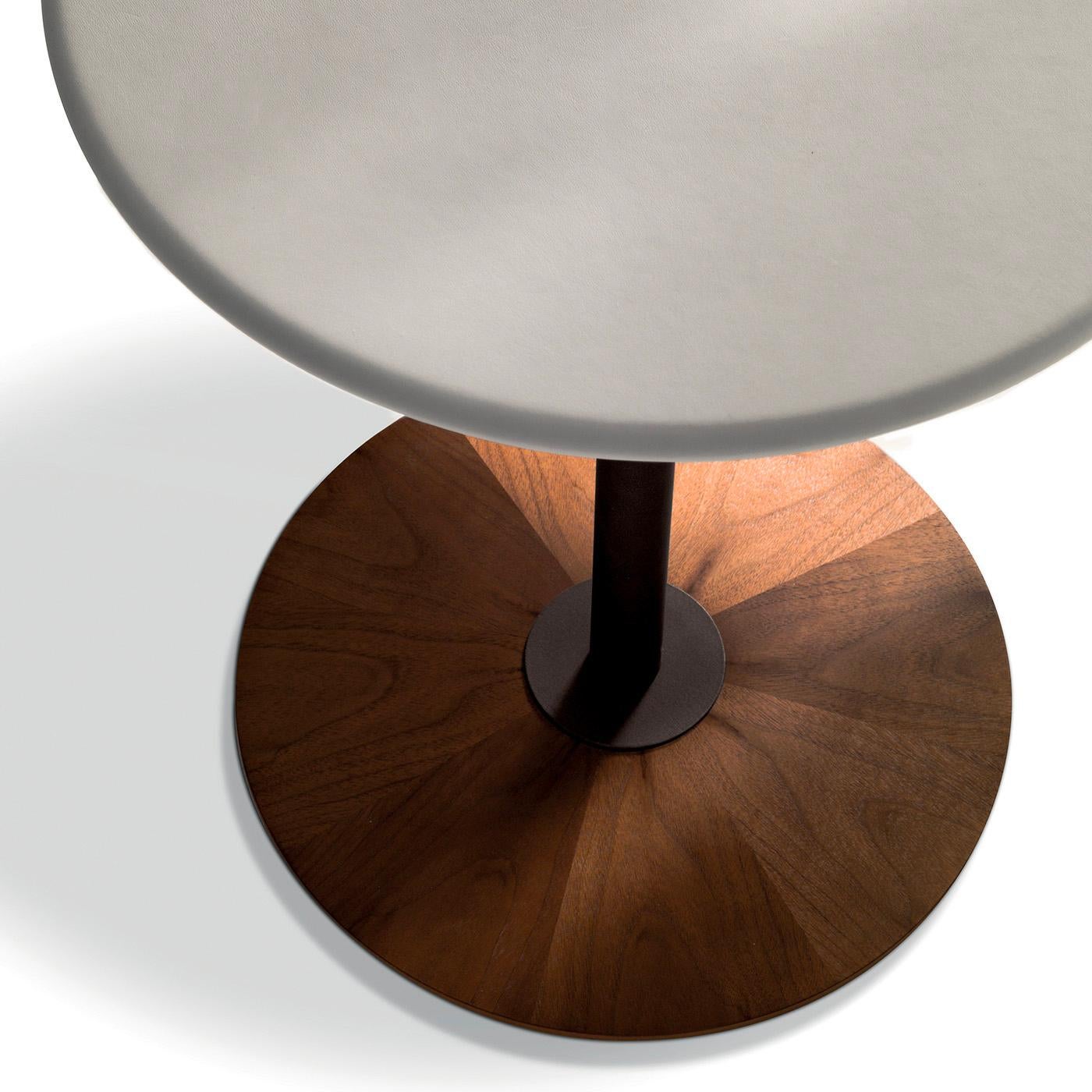 Schlanke, runde Linien definieren diesen minimalistischen Beistelltisch mit einem Sockel aus Canaletto-Nussbaumholz und einem robusten, bronzefarben lackierten Metallfuß, der eine Platte aus Faserholz trägt, die elegant mit hochwertigem Leder