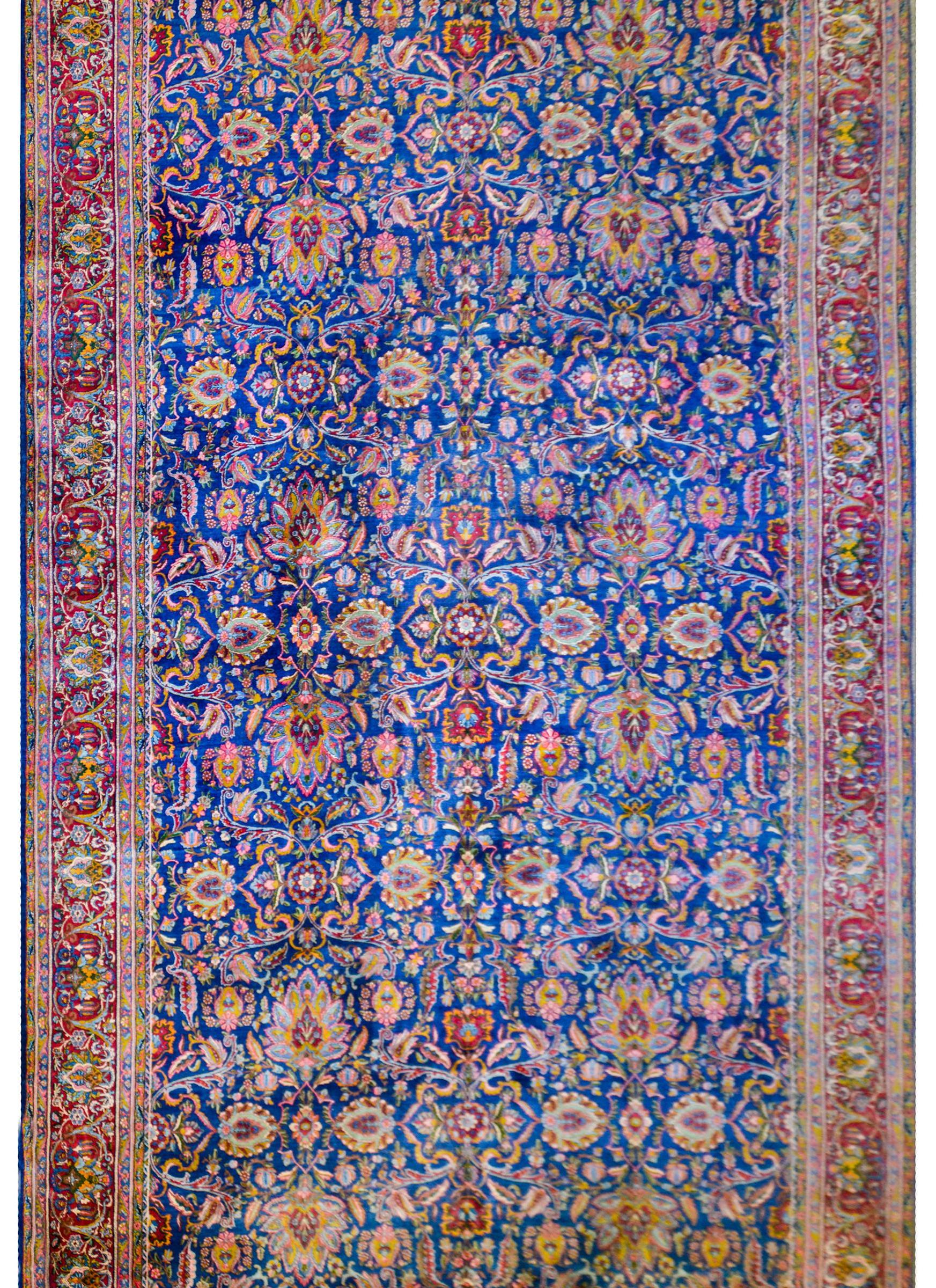 A magical early 20th century Persian Yadz rug with a wonderful densely woven pattern of large and small scale flowers, vines, and leaves rendered in myriad colors on a brilliant indigo background. The border is equally beautiful with a wide central