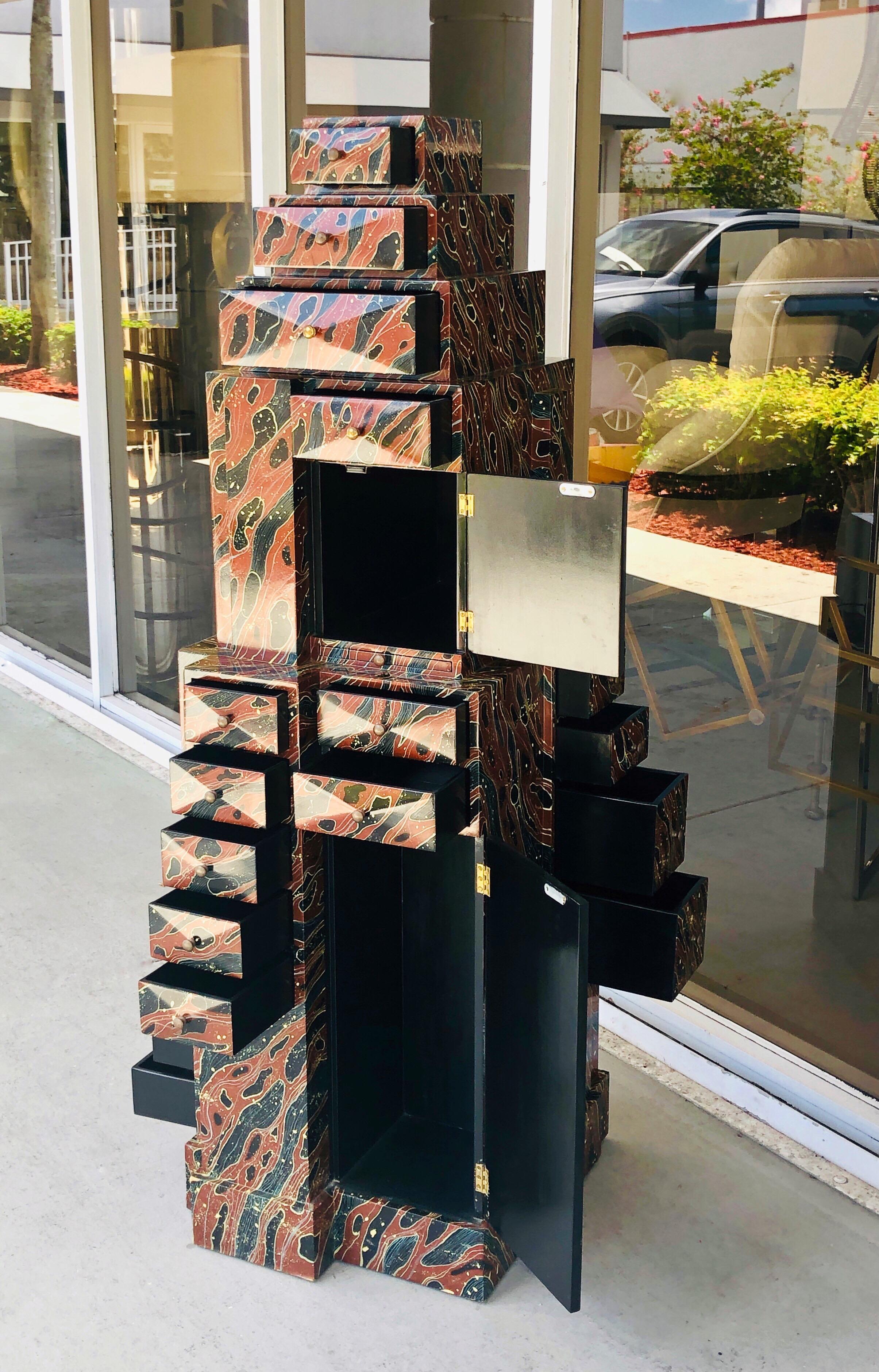 A most unusual piece of art furniture. An sculptural skyscraper cabinet with storage on multiple sides. There are drawers, a pull out writing surface and doors. Brass pulls on drawers. The exterior is had painted I in lacquer, the interior is black