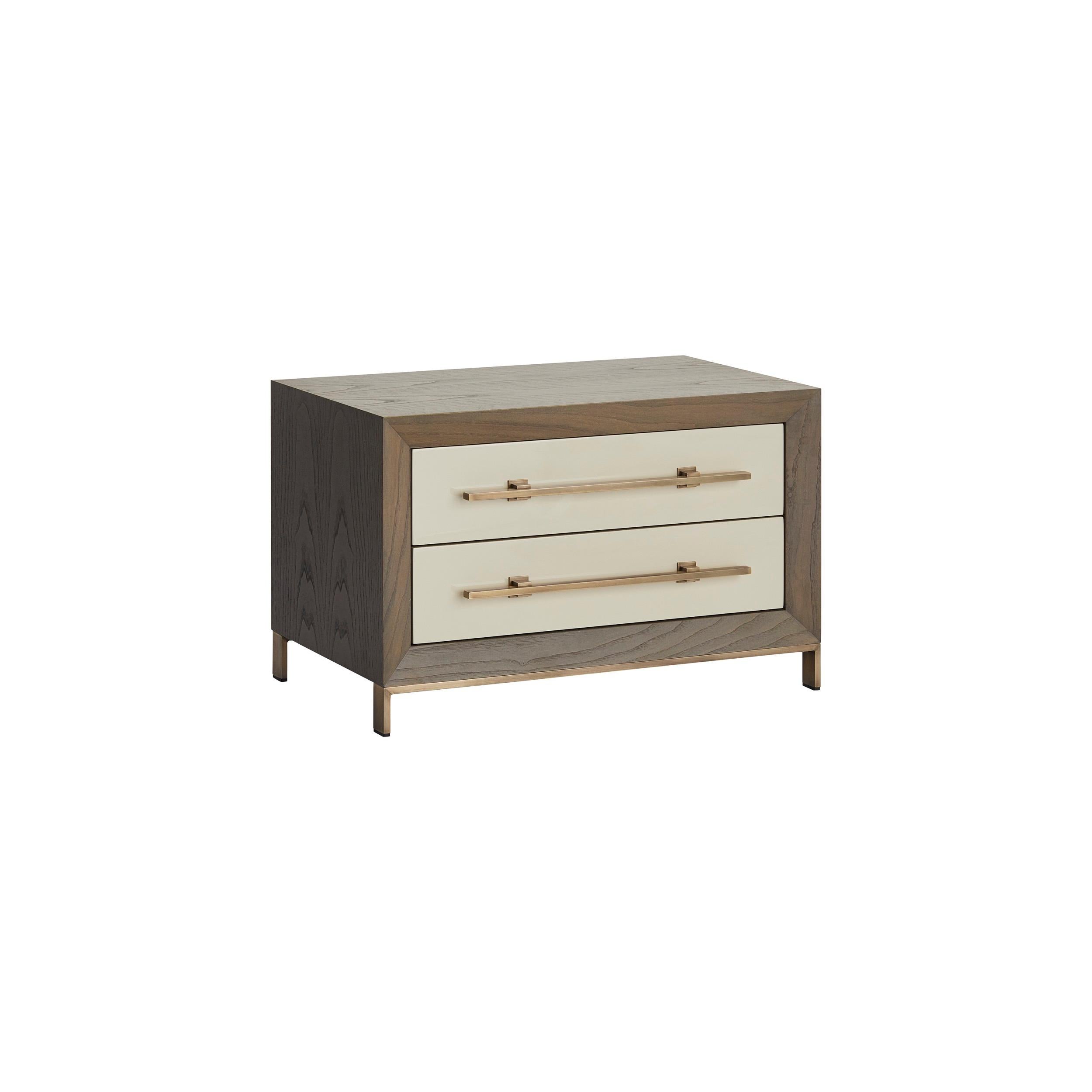 MAGNA is a robust and elegant nightstand, made of veneered wood with two lacquered drawers and embellished with brass details.‎ 

Shown in Matte Chestnut Veneer structure and Matte lacquered drawers, combined with antique brass feet and
