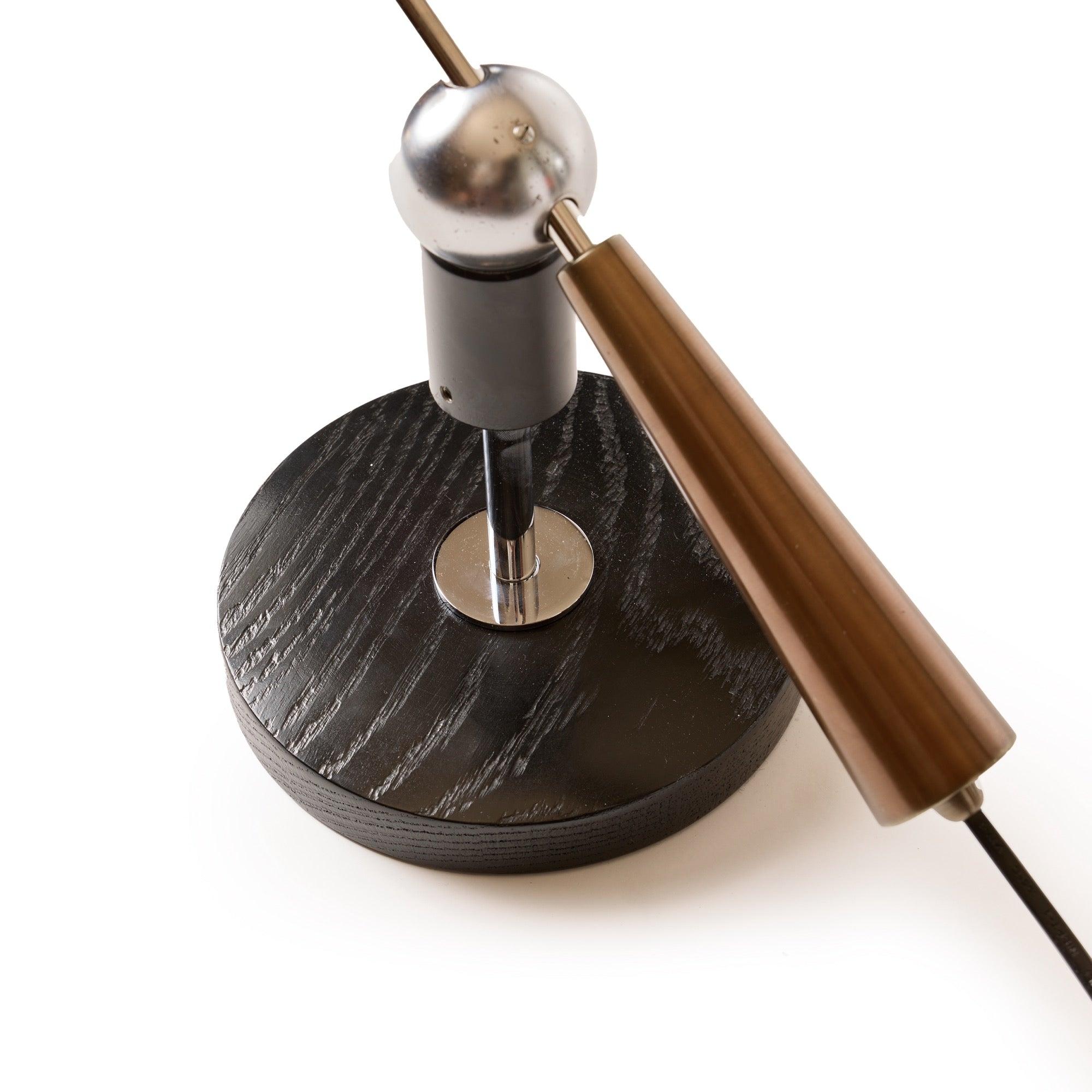 Una lampada da scrivania articolata con un collegamento a sfera magnetica che consente il movimento su una base circolare in Wood.