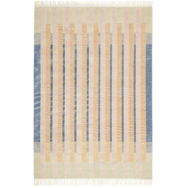 This exquisite rug was designed by Elsa Boch and Ferréol Babin for Karpeta and entirely hand woven. The classic design consists of large bands of contrasting hues crossing over a cream-colored and blue background. The closer one looks at the fabric,