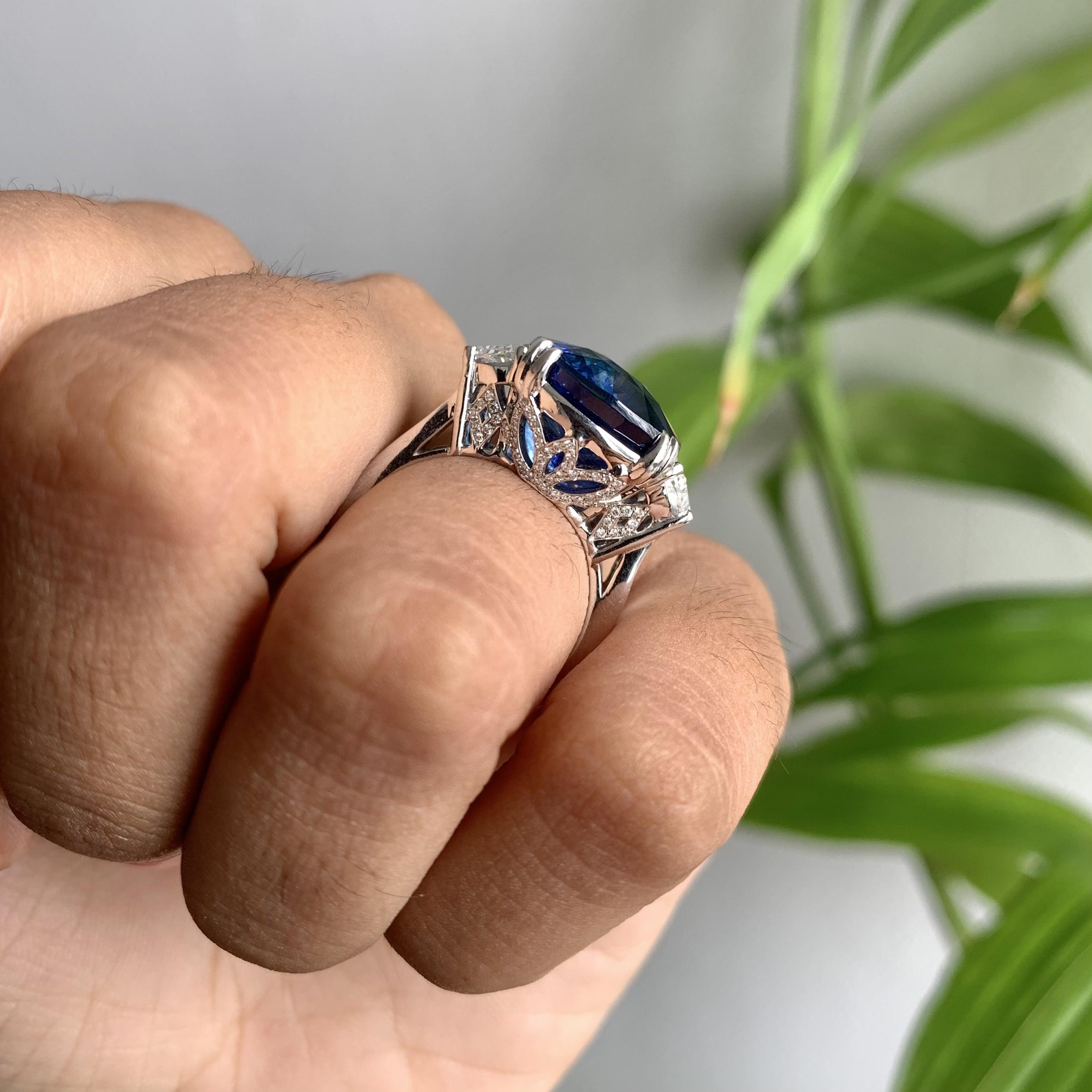 Crafted with utmost precision and finesse, this exquisite masterpiece exudes opulence in every detail. The center of attention is a captivating, high-quality Royal Blue Sapphire, boasting a mesmerizing hue reminiscent of a deep, starry night