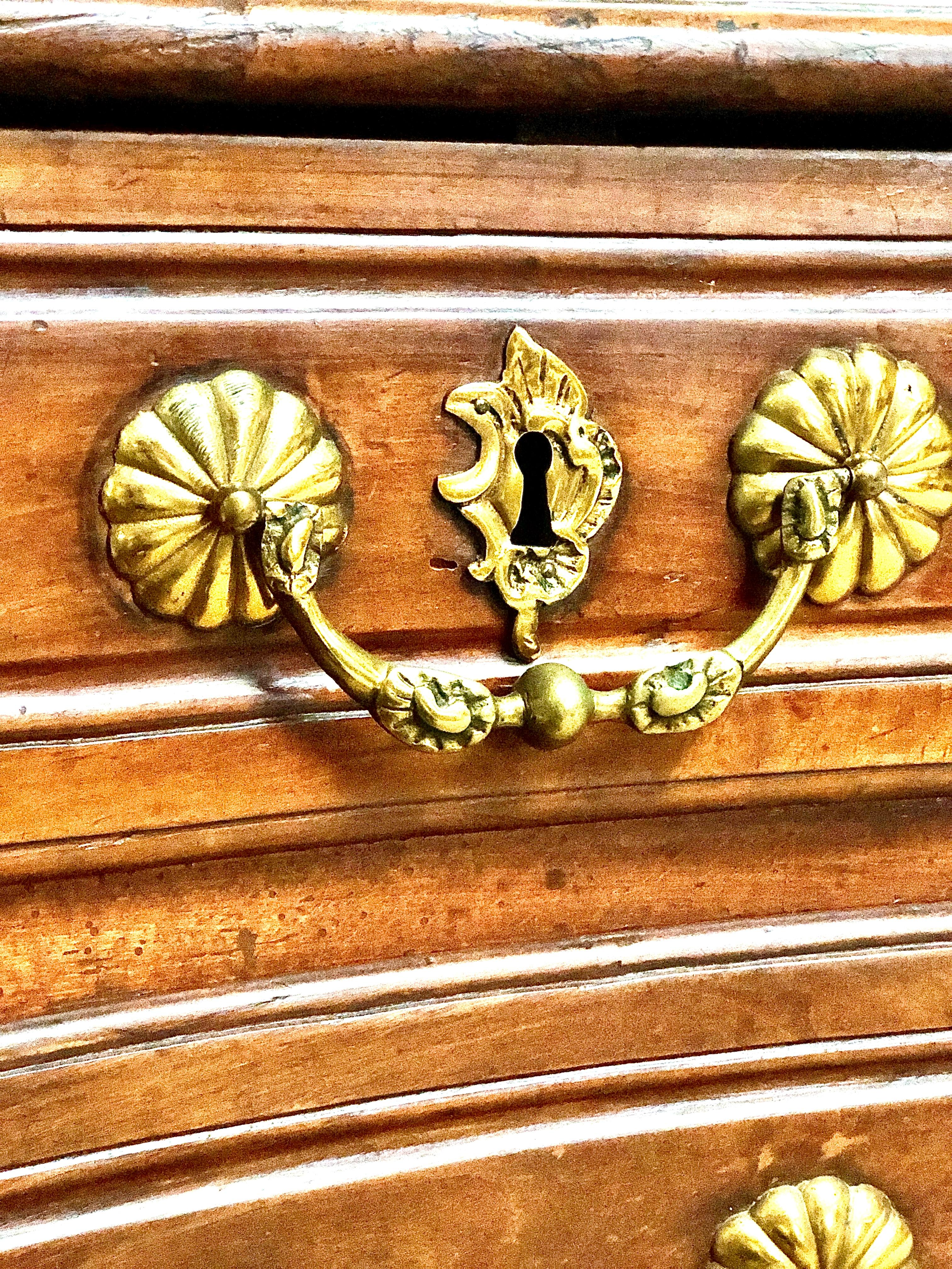 A magnificent 18th century French Louis XV Epoque serpentine fruitwood commode chest of four drawers, standing on elegantly carved feet. Distributed over three rows, each moulded drawer is ornately decorated with gilt bronze handles and escutcheons.