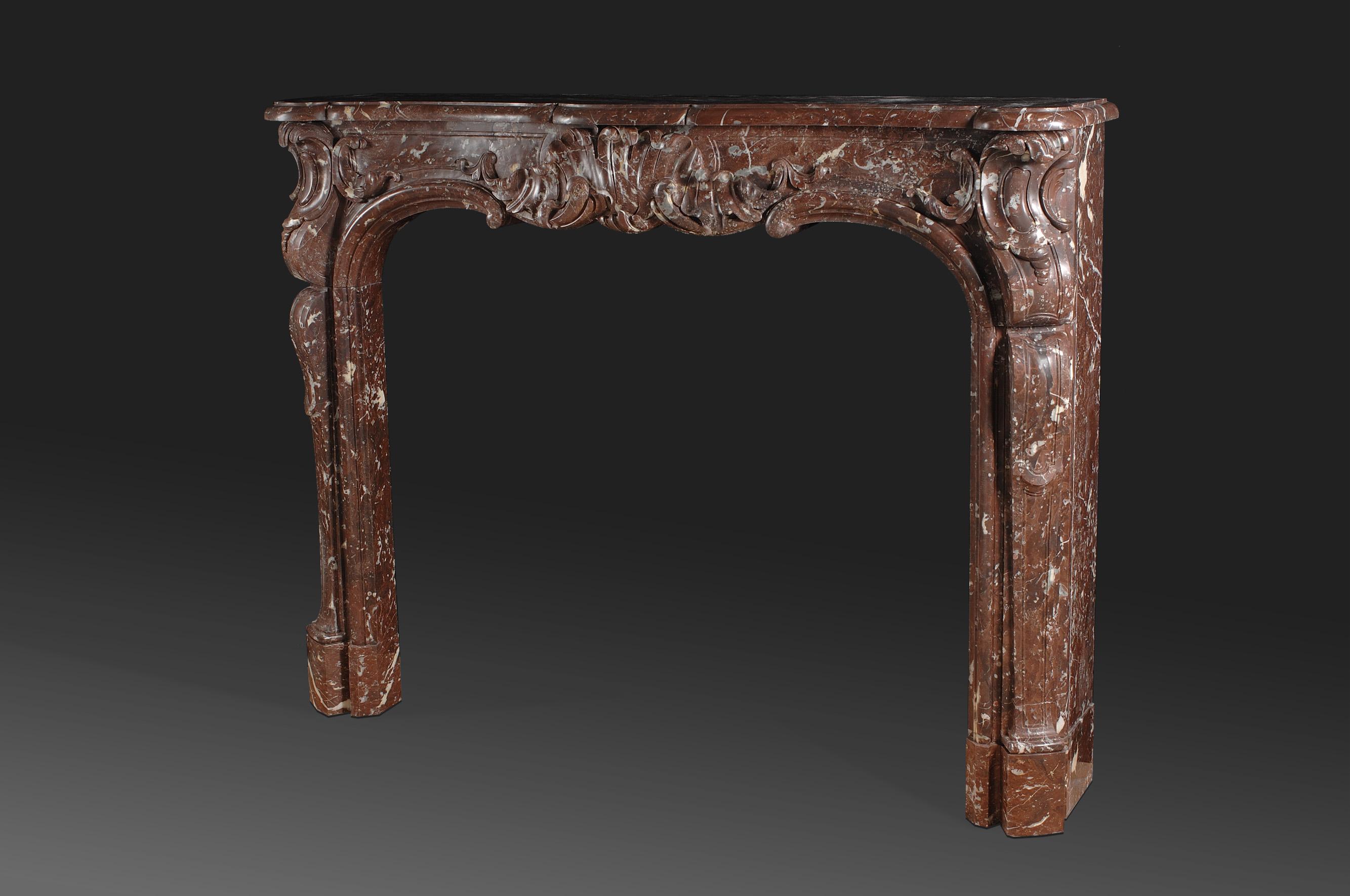Reproduction of a 18th century Louis XV magnificent fireplace. The wide serpentine shelf sits on the shaped frieze which is centered by a very large shell cartouche, is flanked by scrolled endblocks descending on shaped and paneled jambs. Typical 18