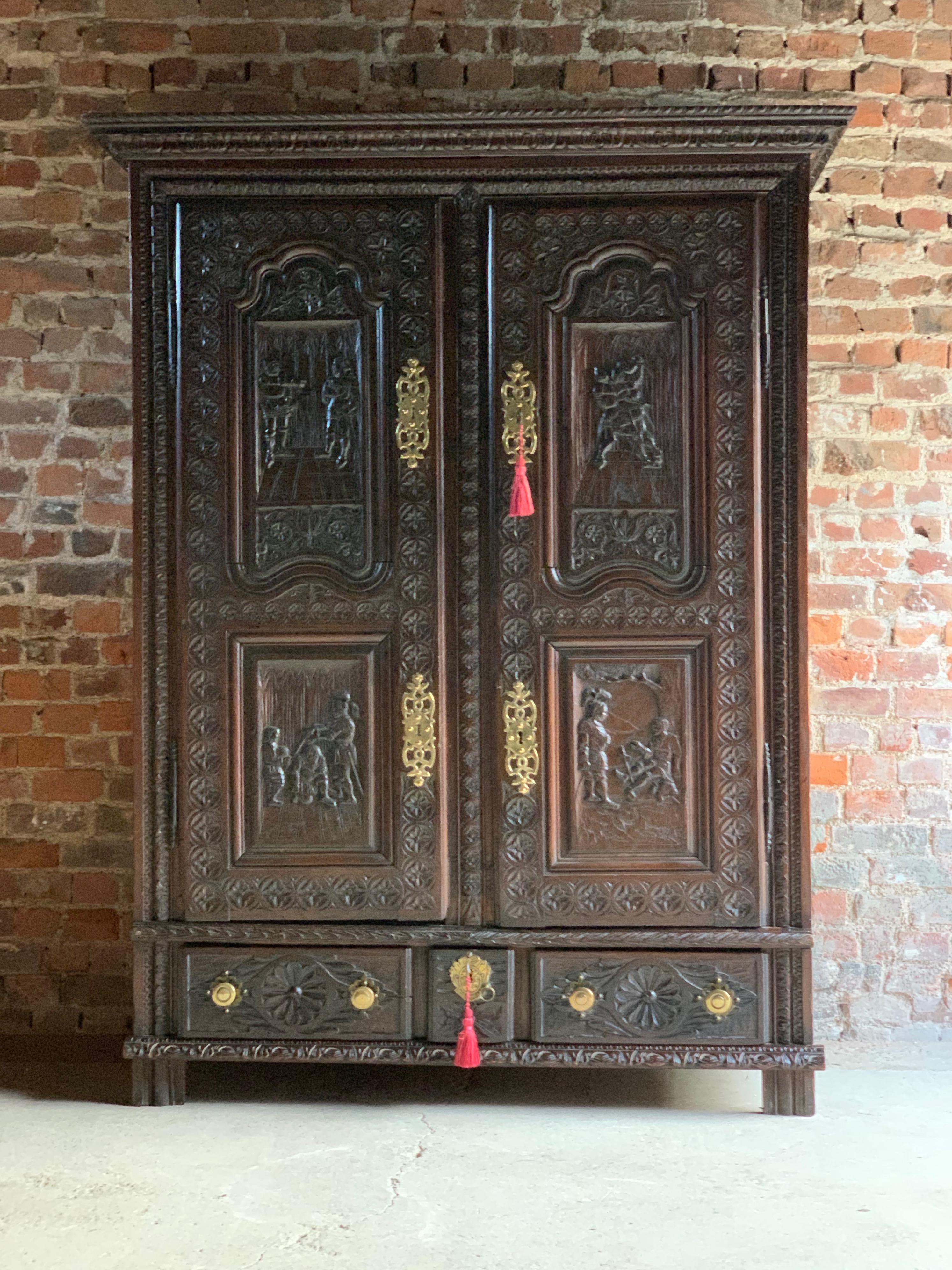 A fabulous 18th century continental solid oak profusely carved cupboard, circa 1740, the corniced top over two heavily carved panel doors, shelves within, over carved base with two long drawers and one small drawer, all with applied brass