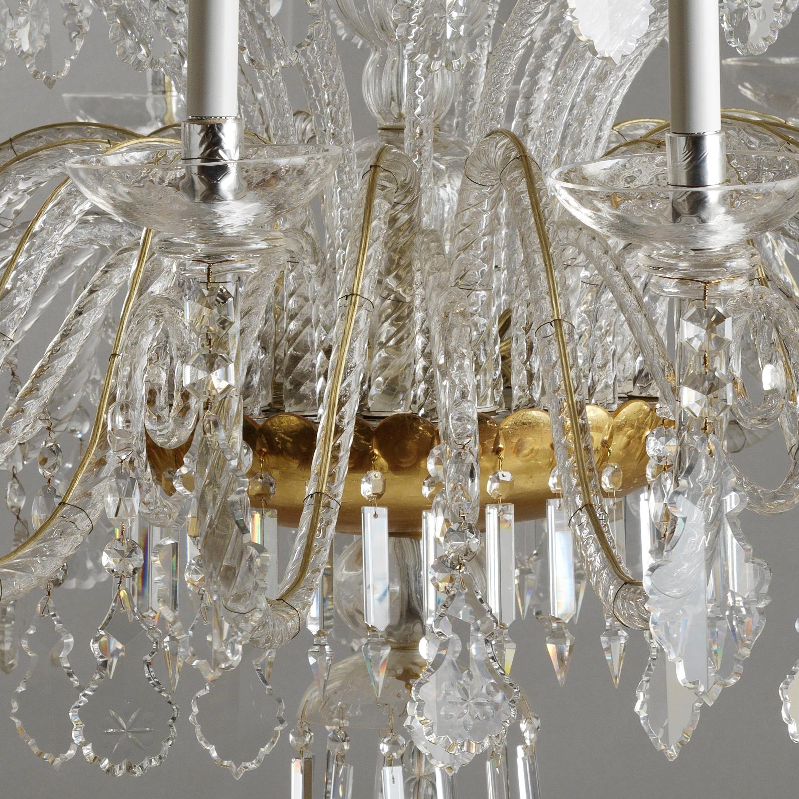 Cet élégant lustre italien en cristal Rococò et verre soufflé de Gherardo Degli Albizzi est réalisé en couleur transparente avec des coupes dorées. Ce lustre est composé de trois couches de branches. La couronne supérieure contient beaucoup de